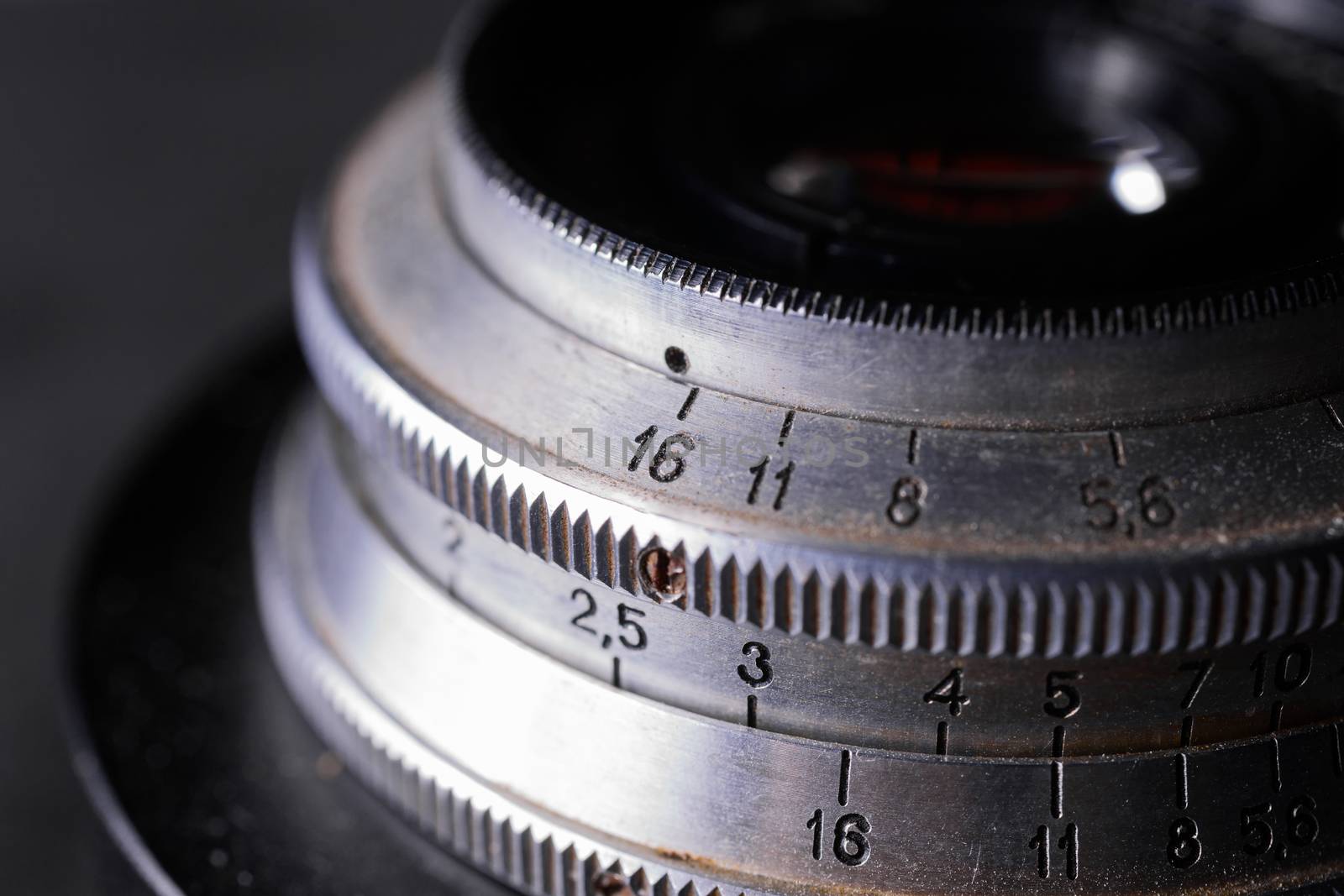 Vintage lens scales symbols closeup. Stock photo with blurred gray background. Aperture symbols and focusing distance sign on lens.