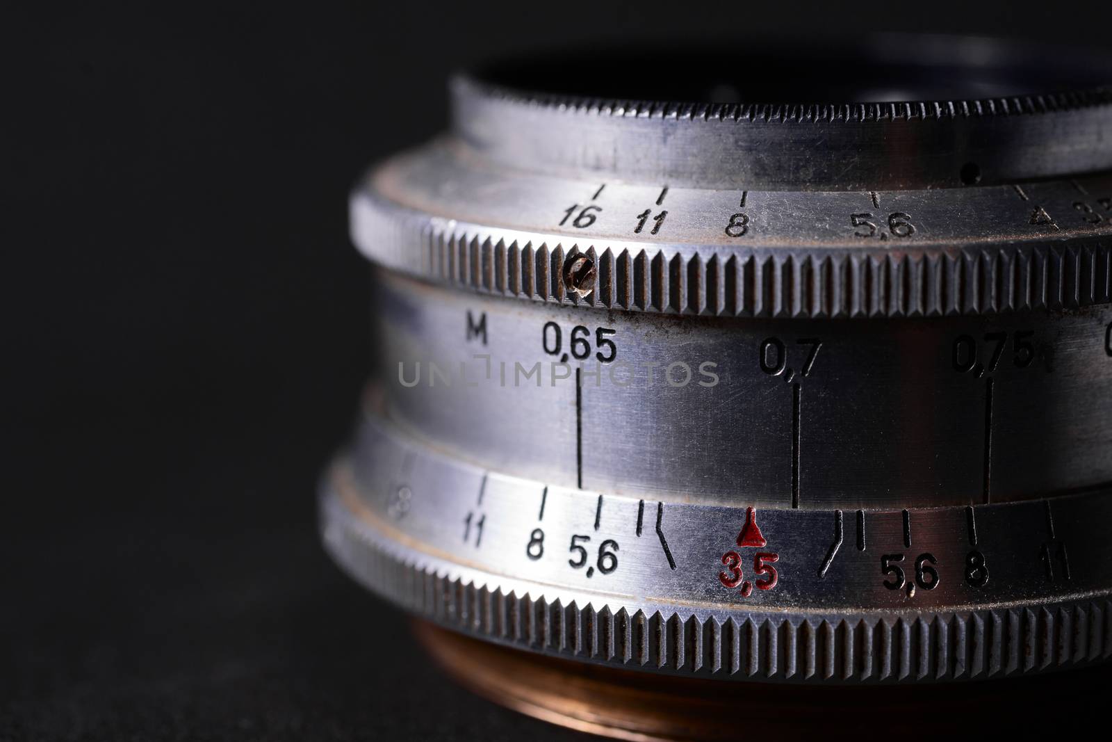 Vintage lens scales symbols closeup. Stock photo with blurred gray background. Aperture symbols and focusing distance sign on lens.