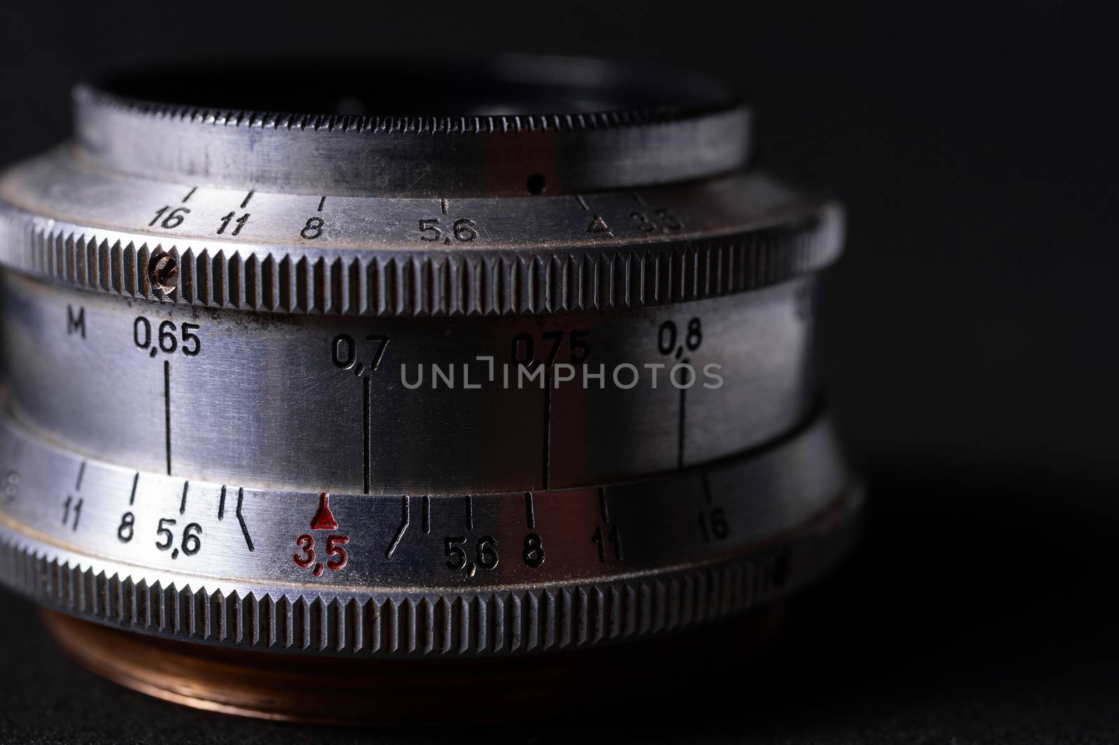 Vintage lens scales symbols closeup. Stock photo with blurred gray background. Aperture symbols and focusing distance sign on lens.
