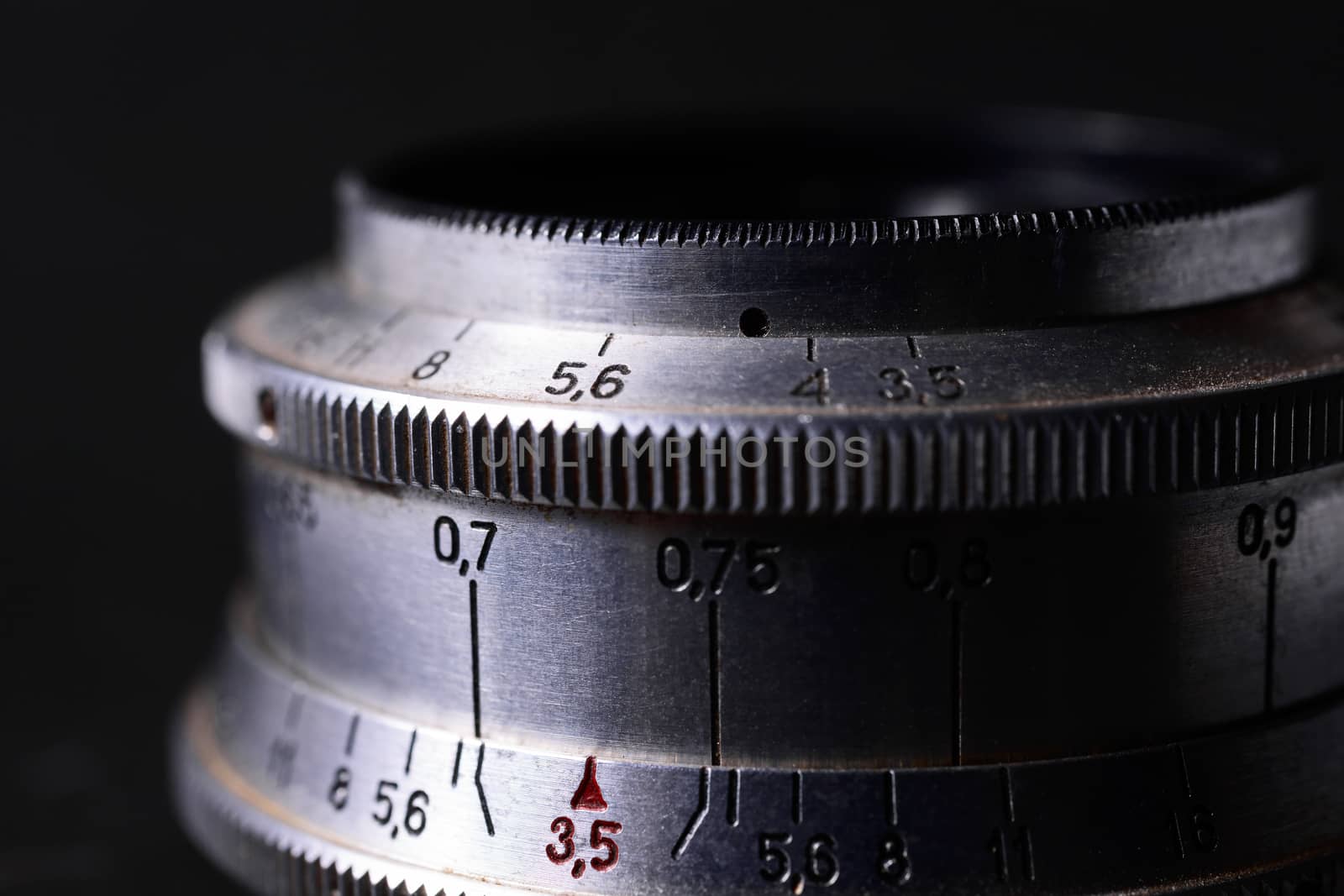 Old vintage lens scales symbols closeup. Photo with blurred gray background. Aperture symbols and focusing distance signs on lens.