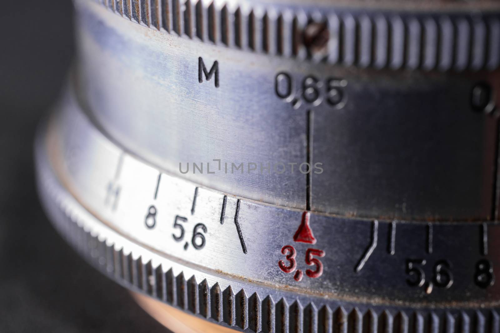 Vintage lens scales symbols closeup. Stock photo with blurred gray background. Aperture symbols and focusing distance sign on lens.