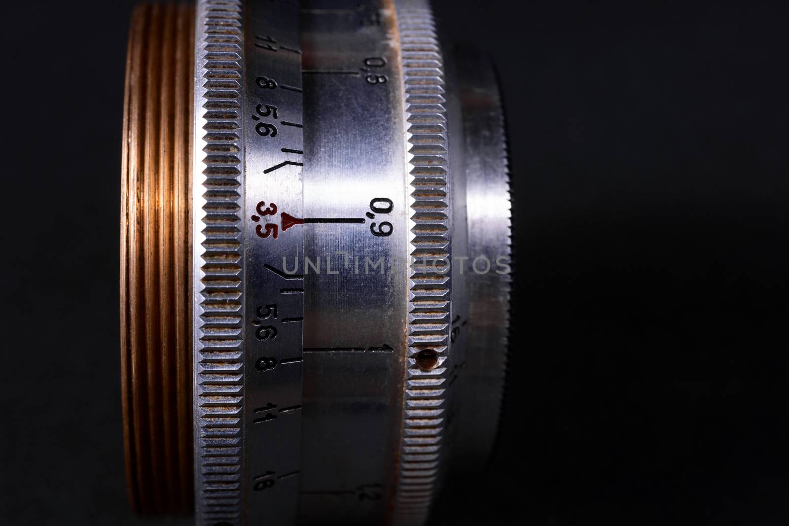 Old vintage lens scales symbols closeup view. Photo with blurred gray background. Aperture symbols and focus distance sign on lens.
