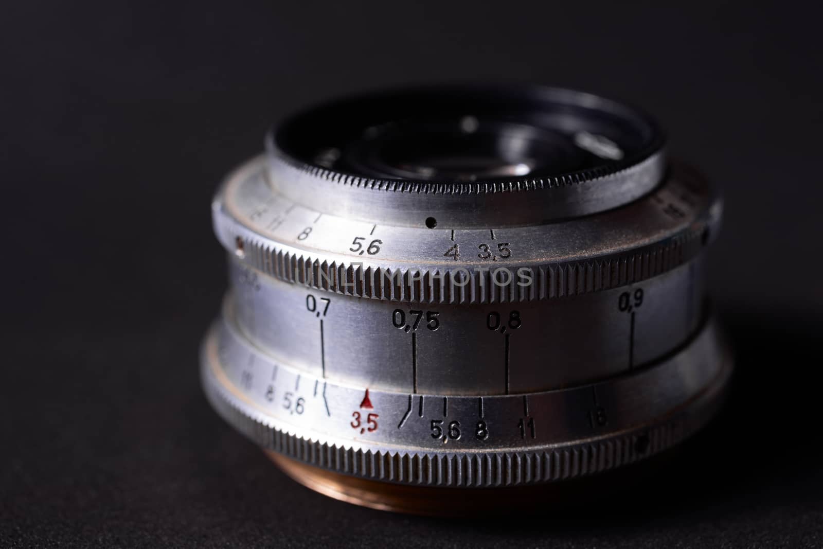 Old vintage lens scales symbols closeup. Photo with blurred gray background. Aperture symbols and focusing distance signs on lens.