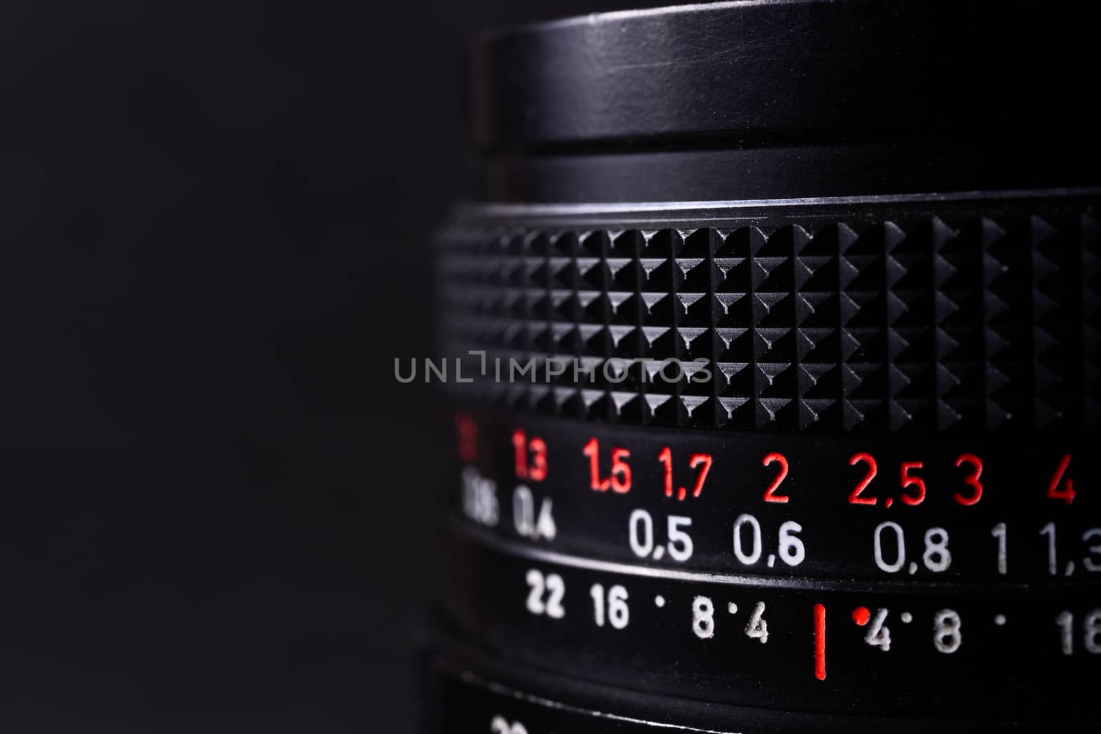 Vintage lens scales symbols closeup. Stock photo with blurred gray background. Aperture symbols and focusing distance signs on lens.