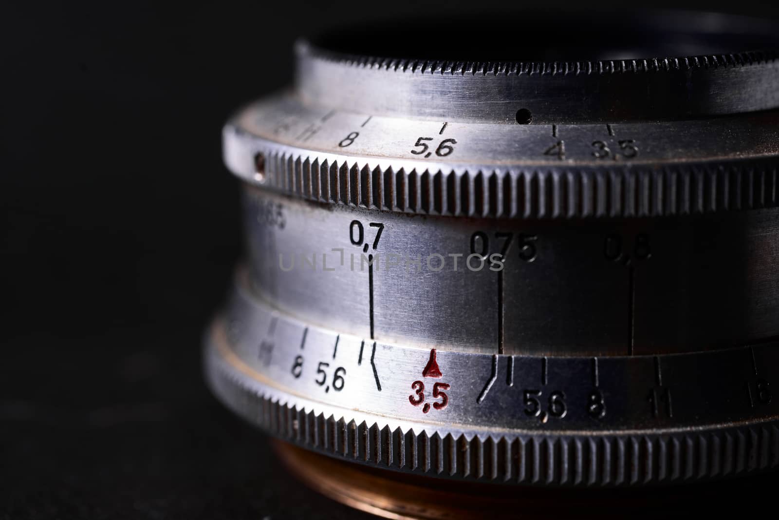 Old vintage lens scales symbols closeup. Photo with blurred gray background. Aperture symbols and focusing distance signs on lens.