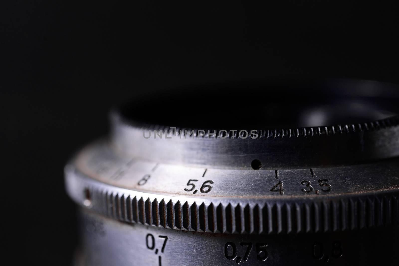 Vintage lens scales symbols closeup. Stock photo with blurred gray background. Aperture symbols and focusing distance sign on lens.