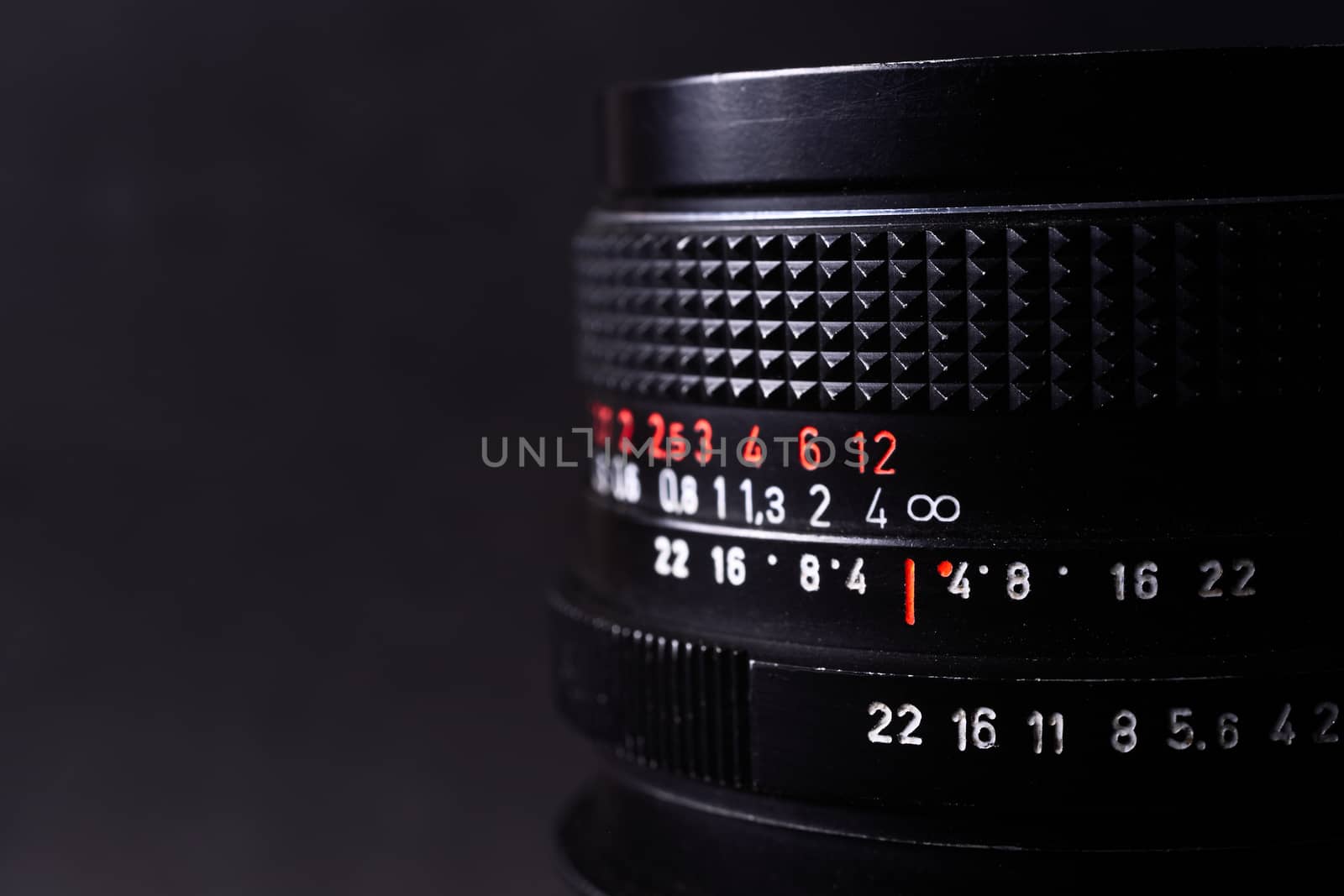 Vintage lens scales symbols closeup. Stock photo with blurred gray background. Aperture symbols and focusing distance signs on lens.