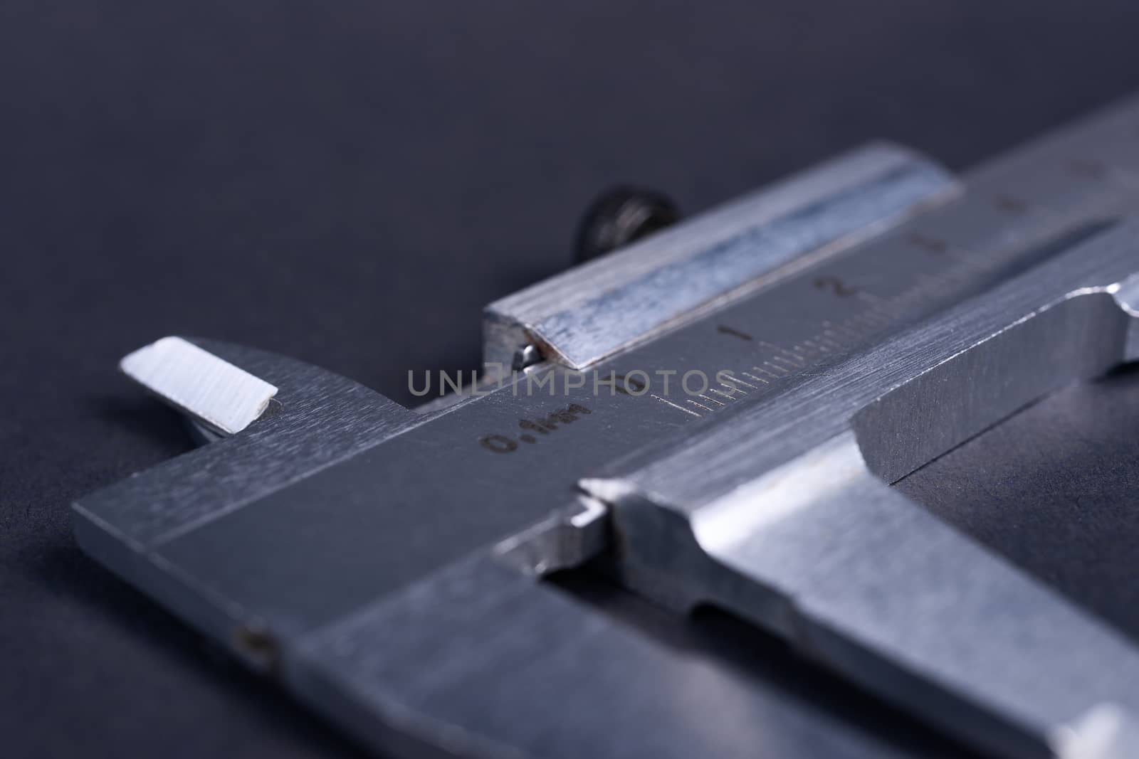 Vintage steel caliper tool closeup. Scale in focus. Tool in very good condition. Scale in metric units, milimeter step. Stock photo on blurred gray background. by alexsdriver