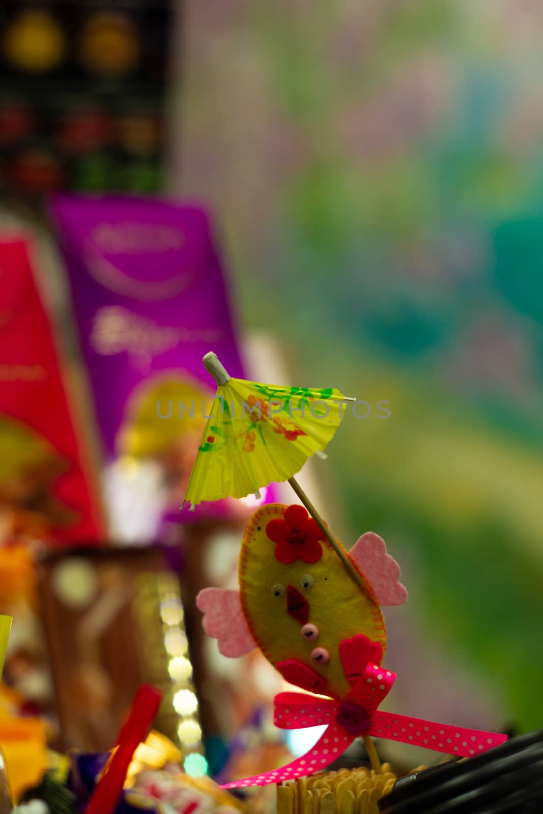 Yellow cocktail paper umbrella on colorful blurred defocused background.