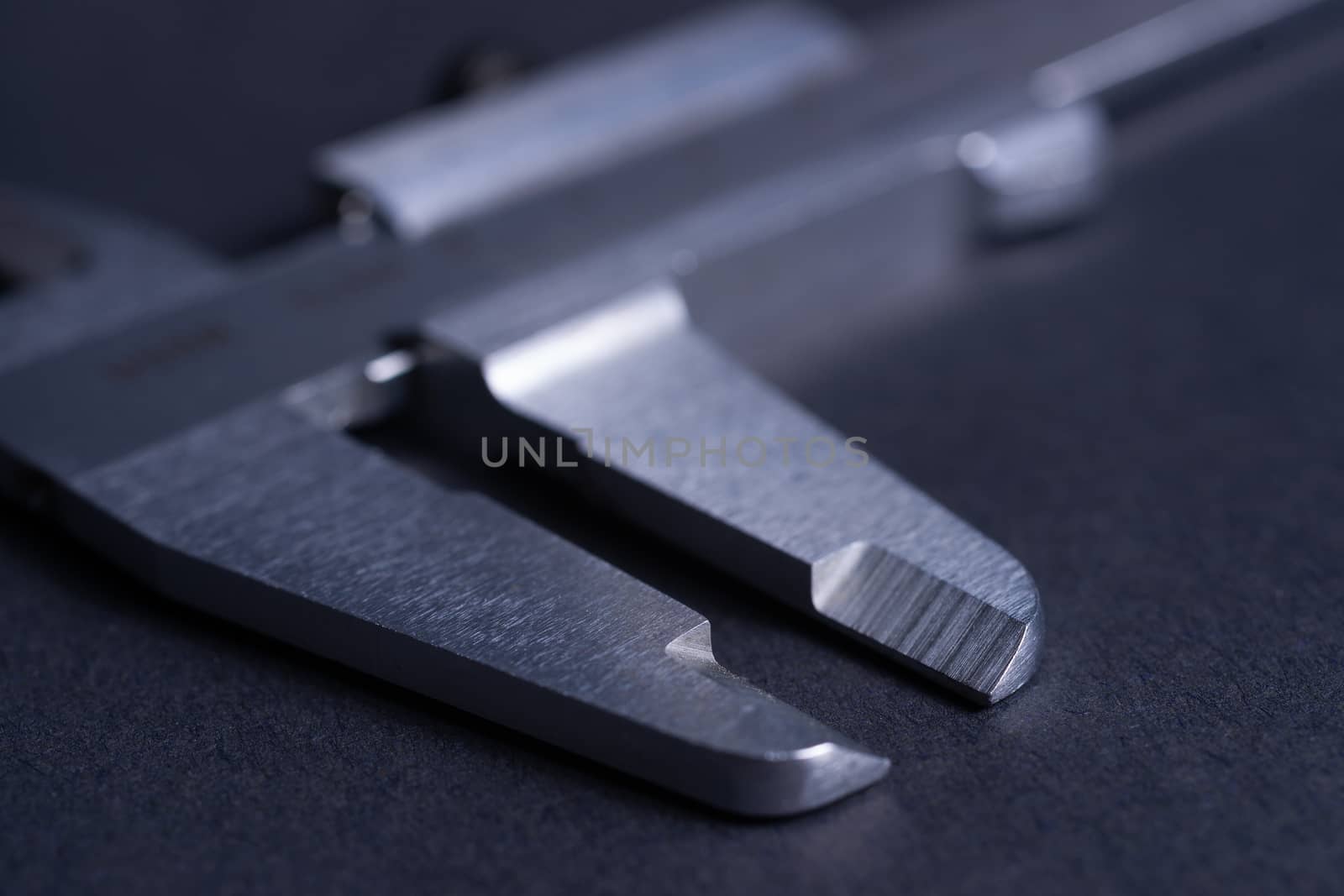 Vintage steel caliper tool closeup. Caliper tips in focus. Tool in very good condition. Scale in metric units, milimeter step. Stock photo on blurred gray background. by alexsdriver