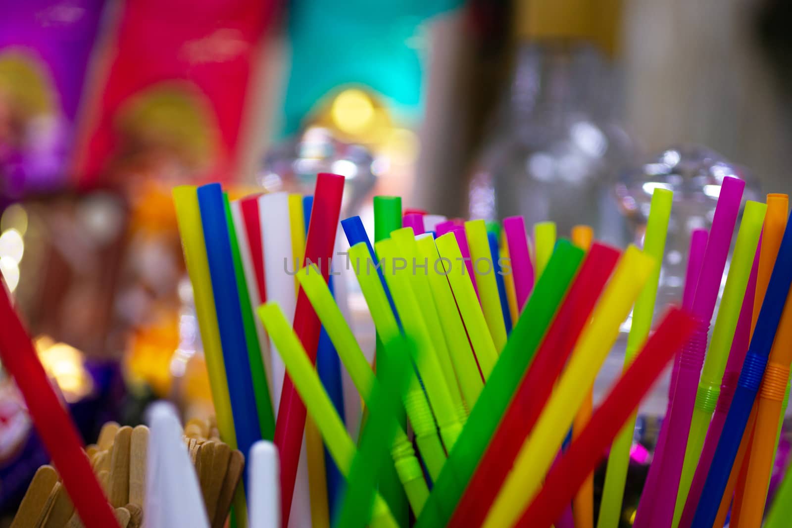 Different colour cocktail plastic pipes on colorful blurred defocused background.