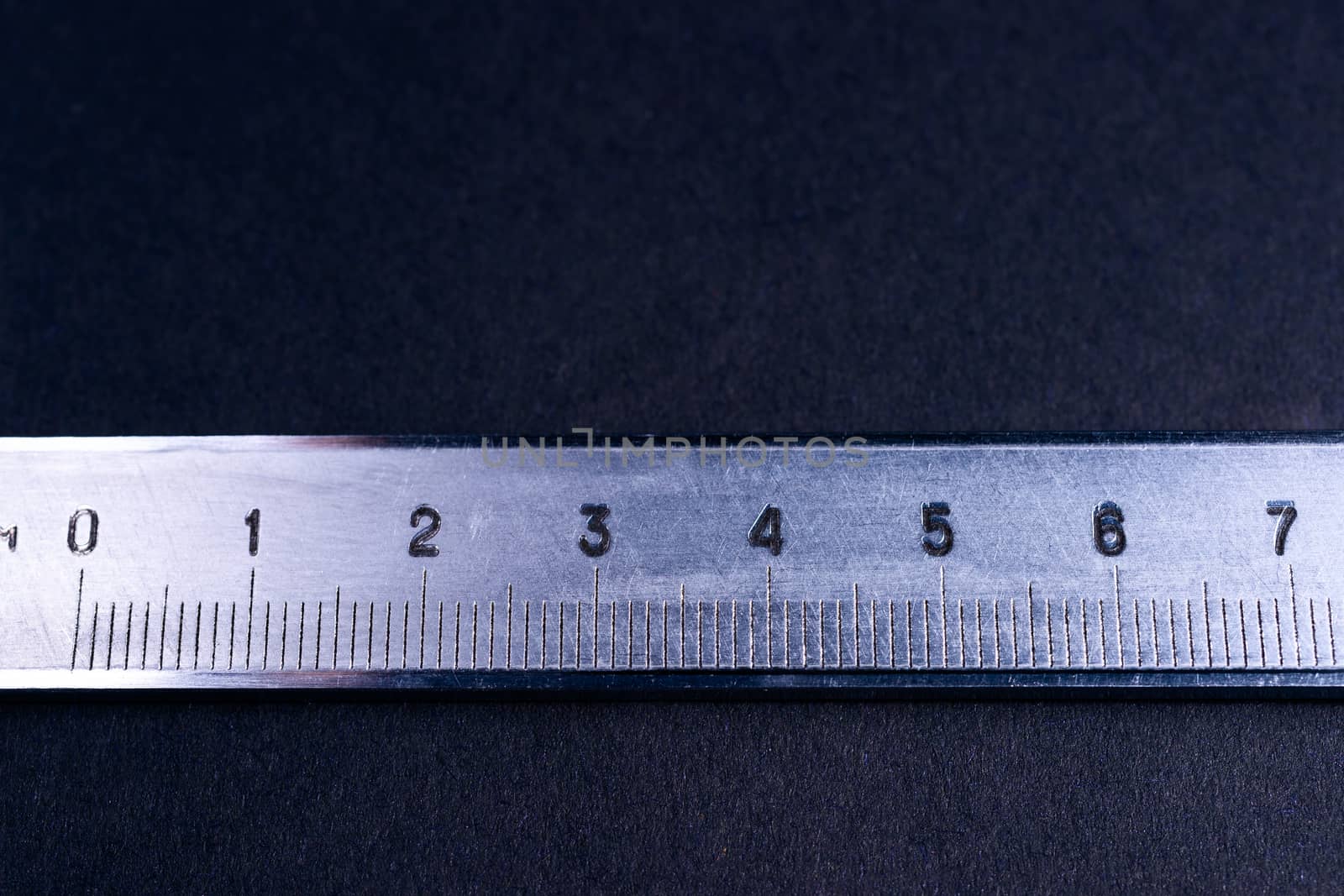 Vintage steel caliper metric scale on dark background. Scale in focus. Tools in very good condition. Stock photo on blurred dark gray background.