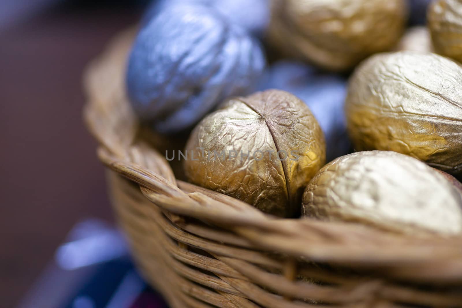 Silver and golden holiday candy nuts in a wicker basket.