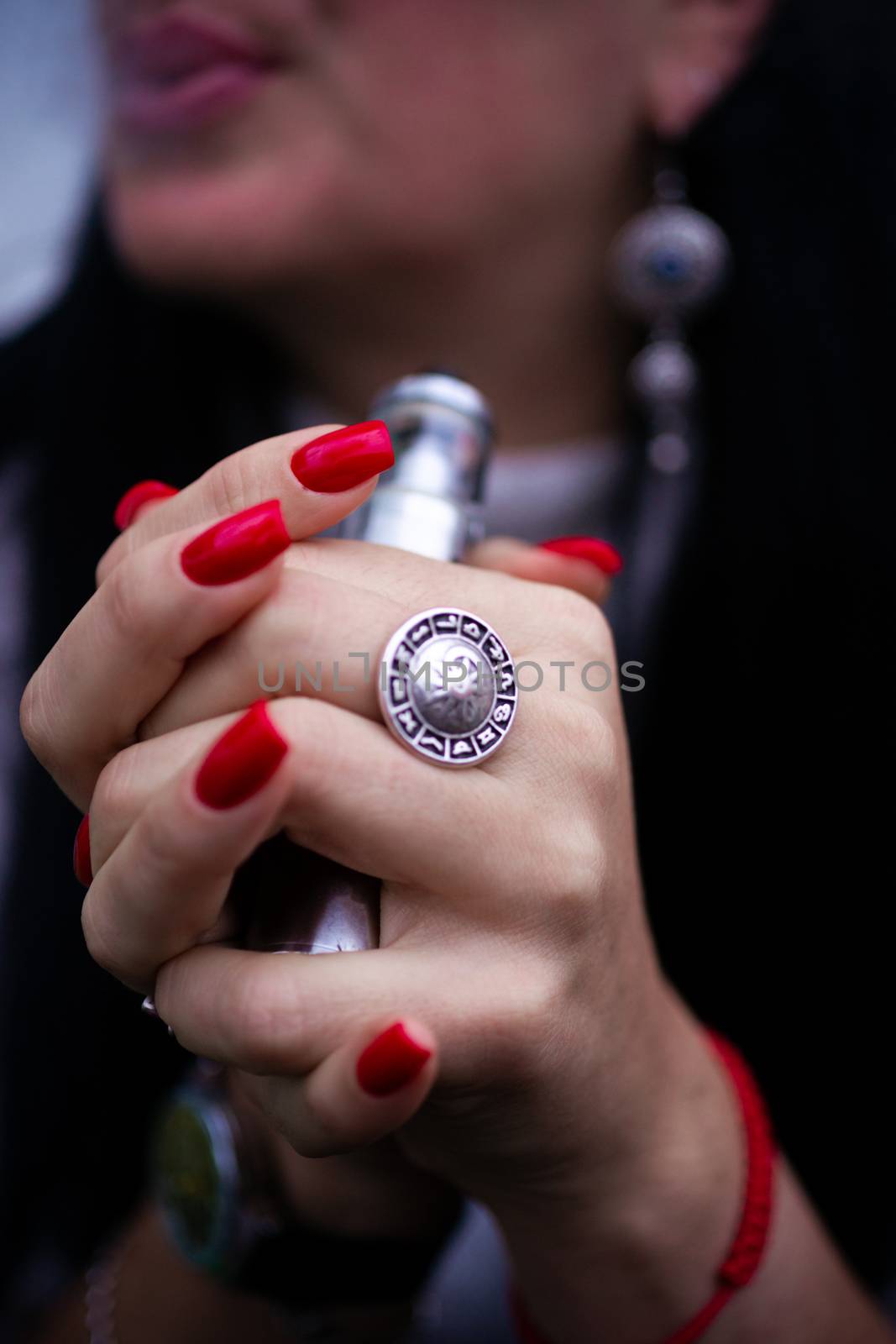 Caucasian woman with red nails manicure and antique ring on finger holds small vape. Smoking alternative vay. Life without cigarettes. Woman-vaper. Small e-cigarette.