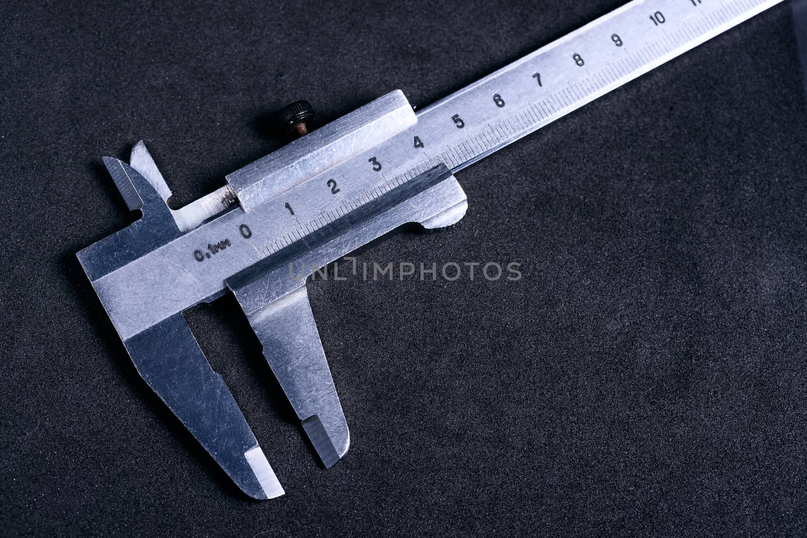 Vintage steel caliper on dark background. Scale in focus. Tool in very good condition. Stock photo on blurred gray background.