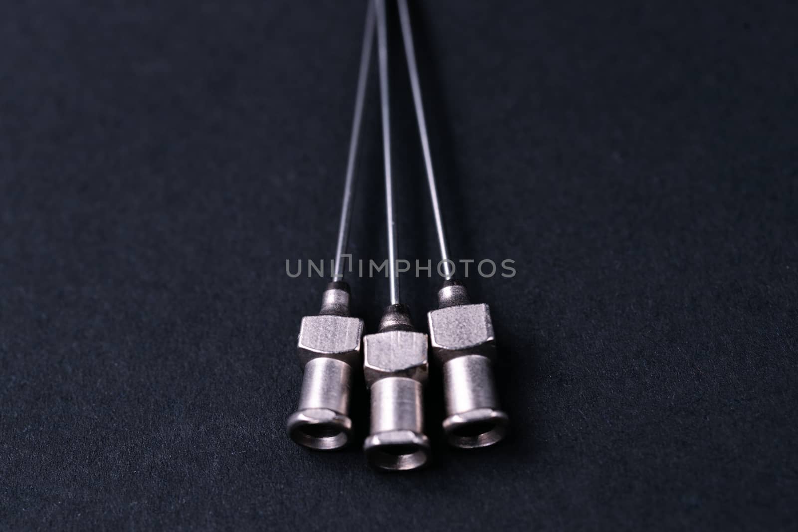 Old rare metallic medical needles isolated on gray background. Needles new and clean. Top view. Sharp needle tips not visible on photo.