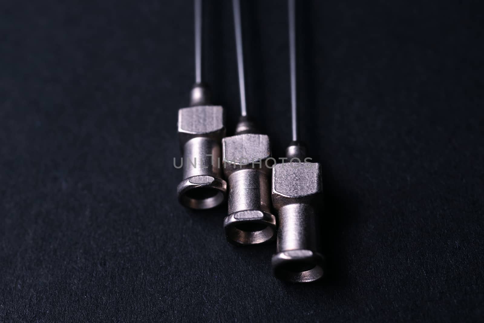 Old rare metallic medical needles isolated on gray background. Needles new and clean. Top view. Sharp needle tips not visible on photo.
