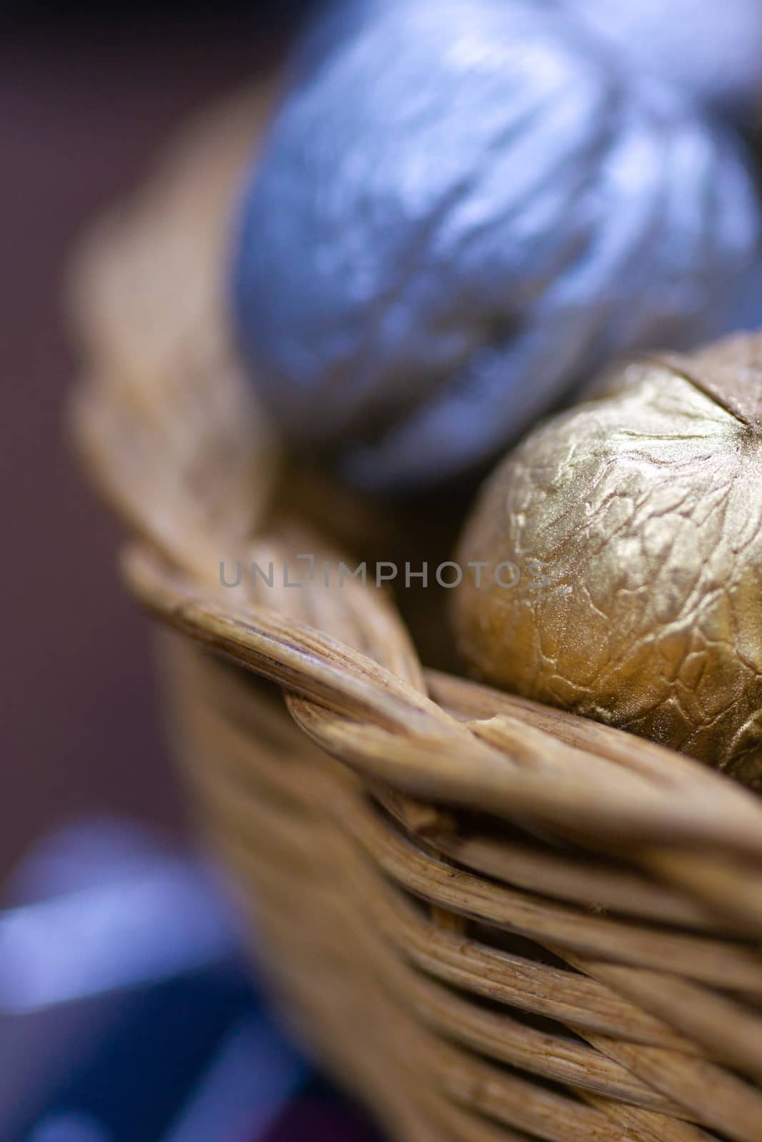 Silver and golden holiday candy nuts in a wicker basket.