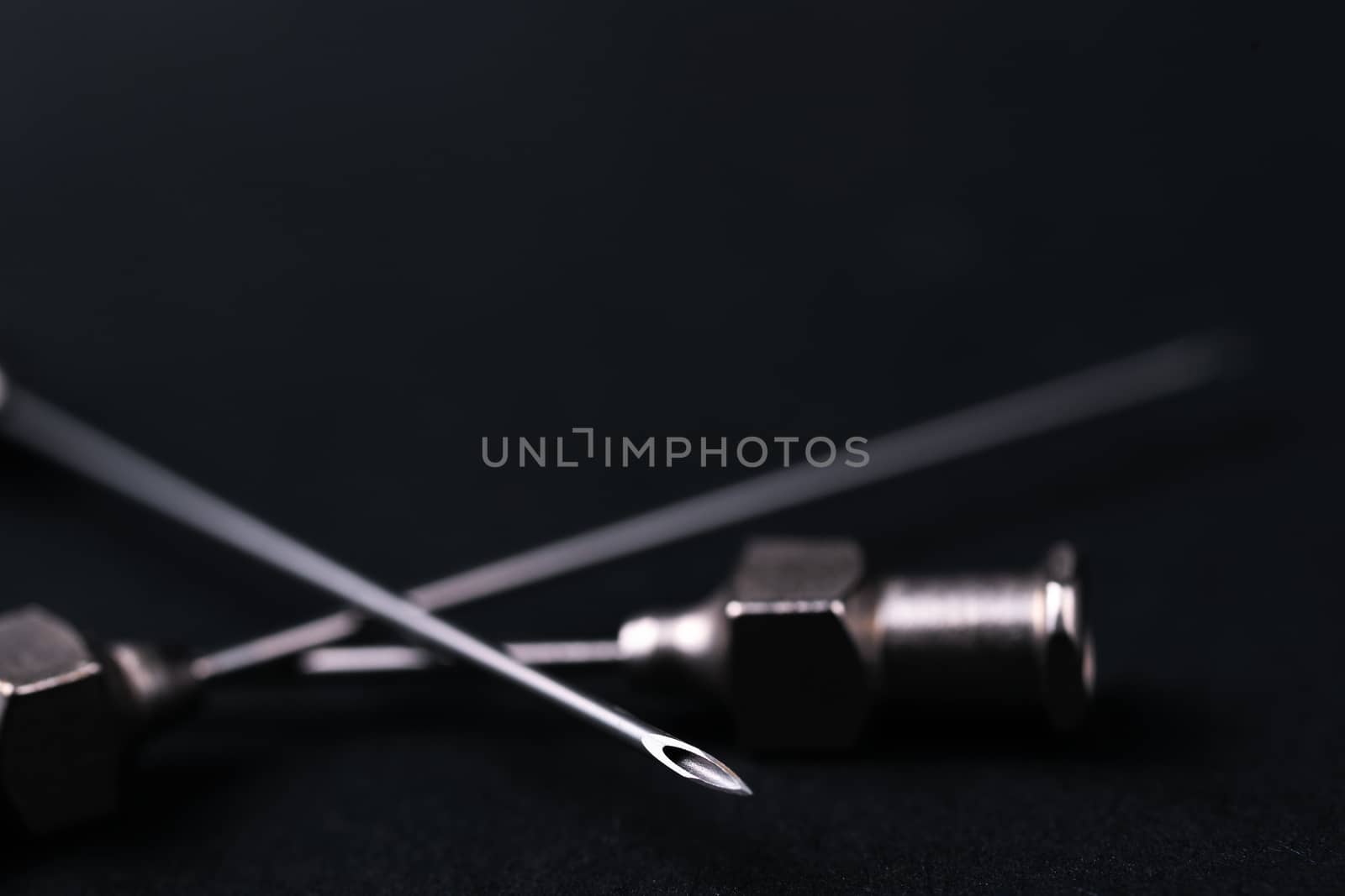 Old rare metallic medical needles isolated on gray background. Needles new and clean. Top view. Sharp needle tips and defocused background.