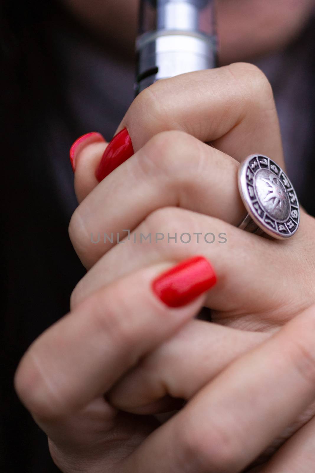 Caucasian woman with red nails manicure and antique ring on finger holds small vape. Smoking alternative vay. Life without cigarettes. Woman-vaper. Small e-cigarette.