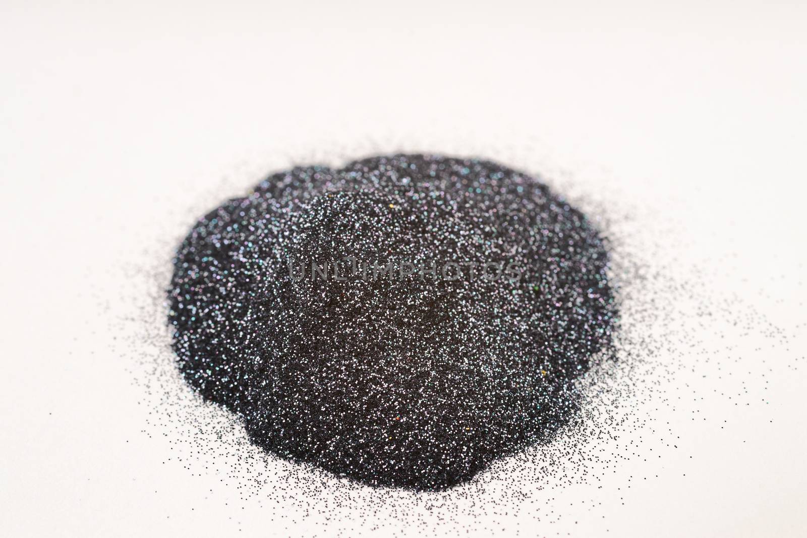 A small bunch of silver blue nail gritter for manicure. Gray tone glitter shining on daylight. Stock photo isolated on white background. Varnish topping on paper.