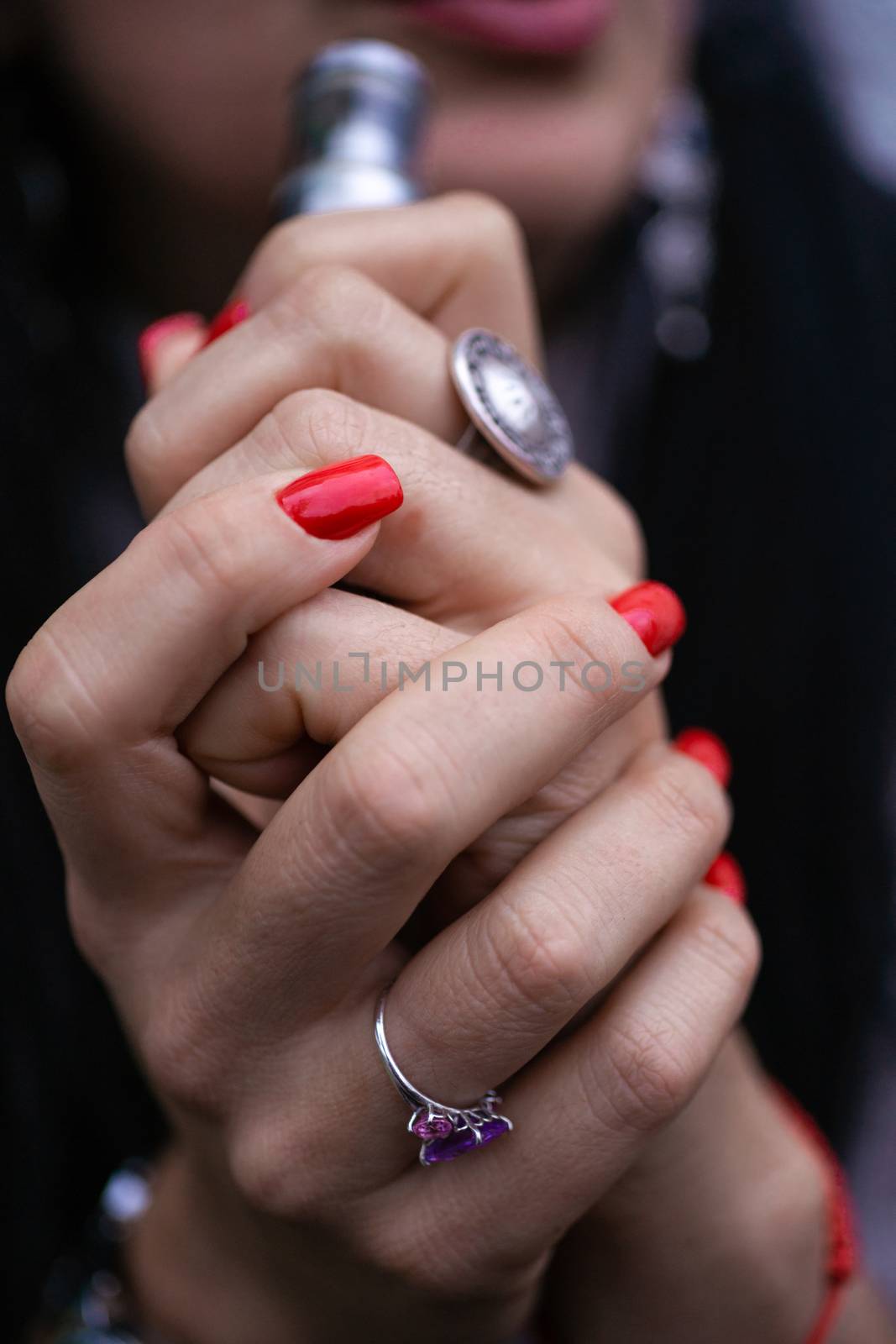 Caucasian woman with red nails manicure and antique ring on finger holds small vape. Smoking alternative vay. Life without cigarettes. Woman-vaper. Small e-cigarette. by alexsdriver