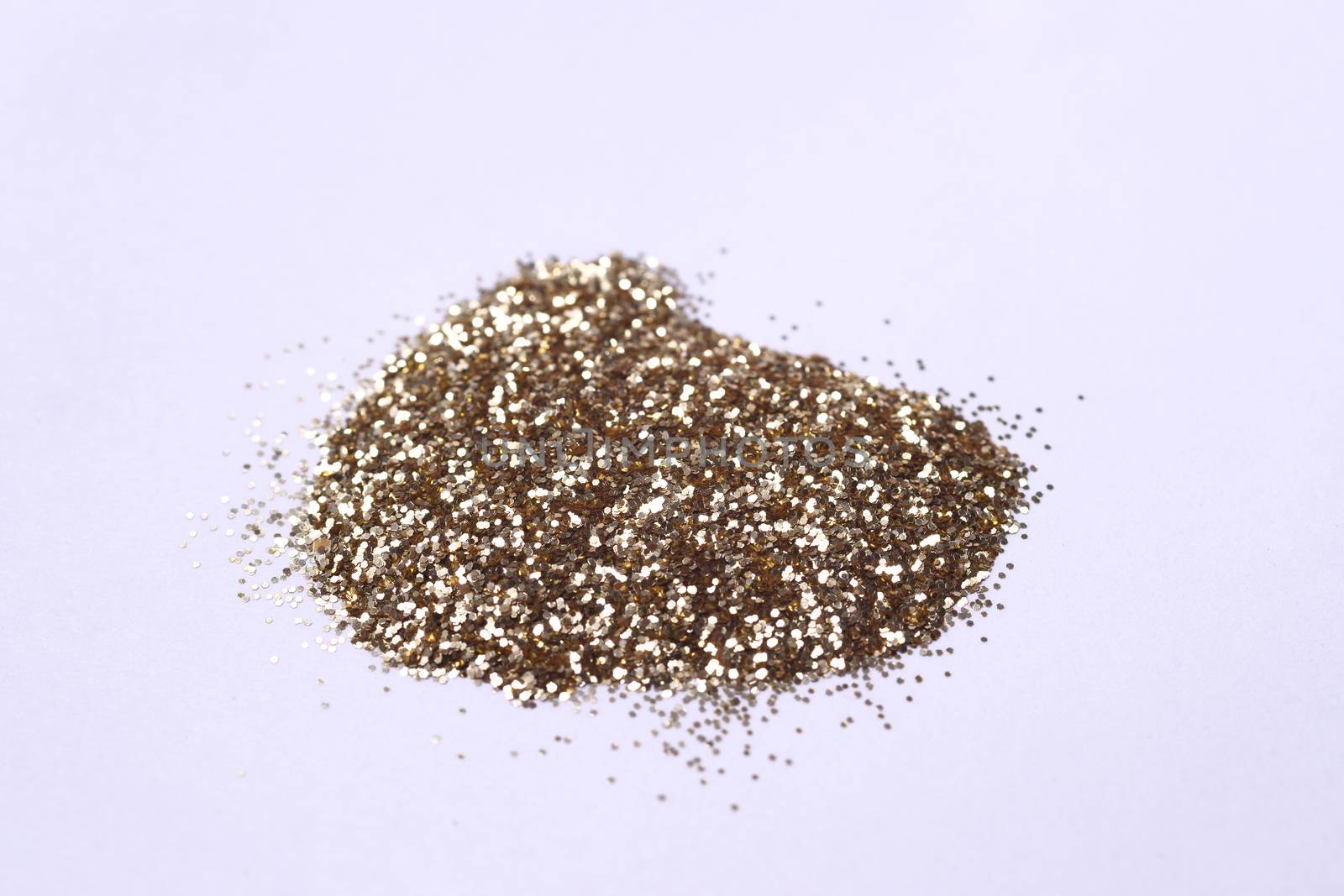 A small bunch of golden nail gritter for manicure. Yellow tone glitter shining on daylight. Stock photo isolated on white background. Varnish topping on paper. Up to down view.