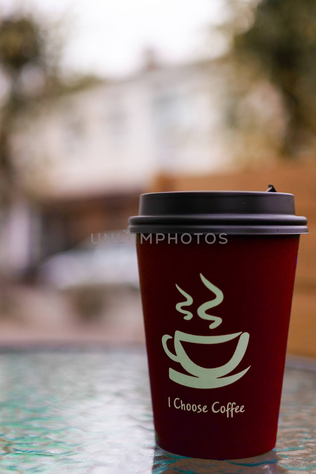 Red coffee paper cup on glass clear table. On cup wrote: "I choose coffee". Beginning a good day!