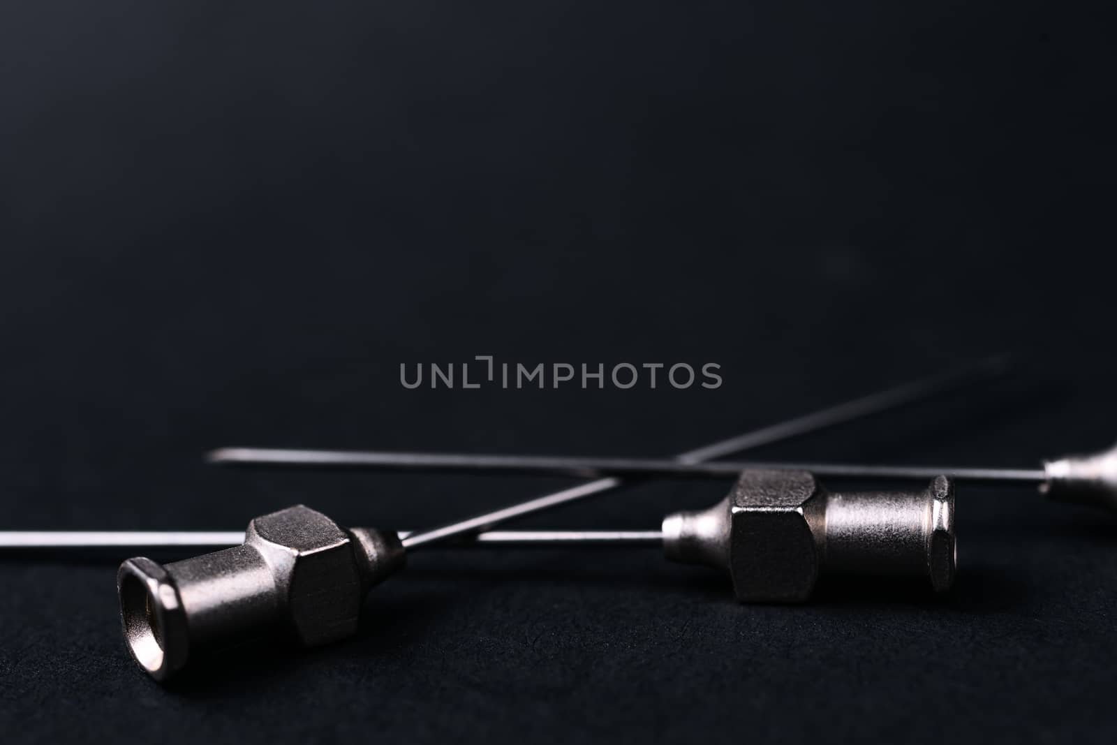 Old rare metallic medical needles isolated on gray background. Needles new and clean. Top view. Sharp needle tips and full metal body.