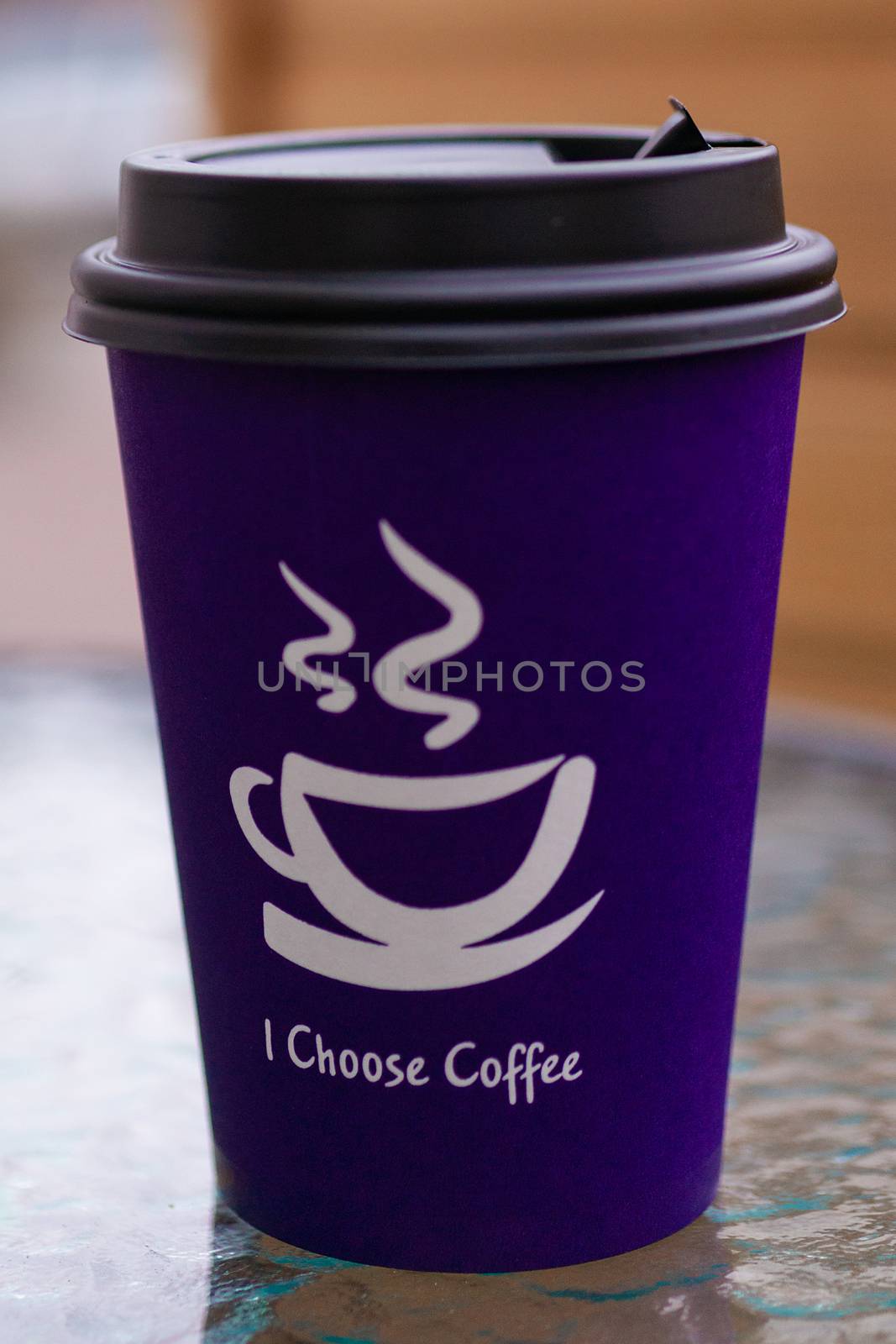 Purple coffee paper cup on glass clear table. On cup wrote: "I choose coffee". Beginning a good day!