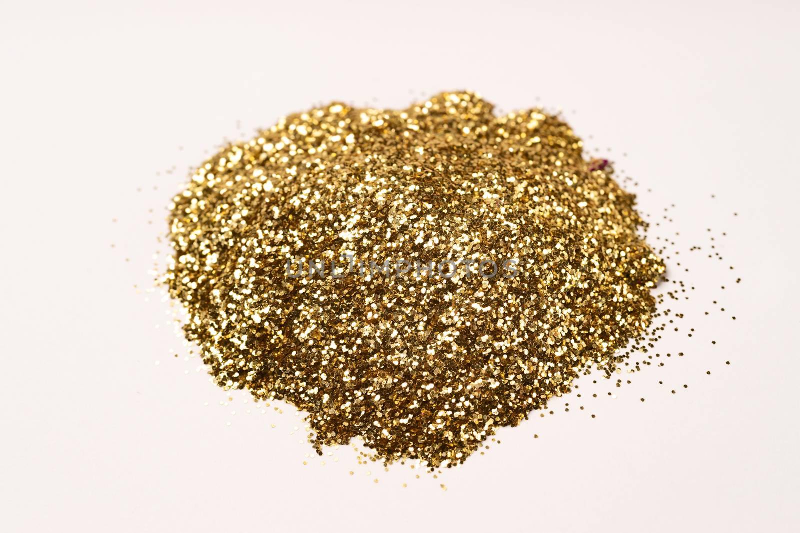 A bunch of golden nail gritter for manicure. Golden glitter shining on daylight. Stock photo isolated on white background. Varnish topping.