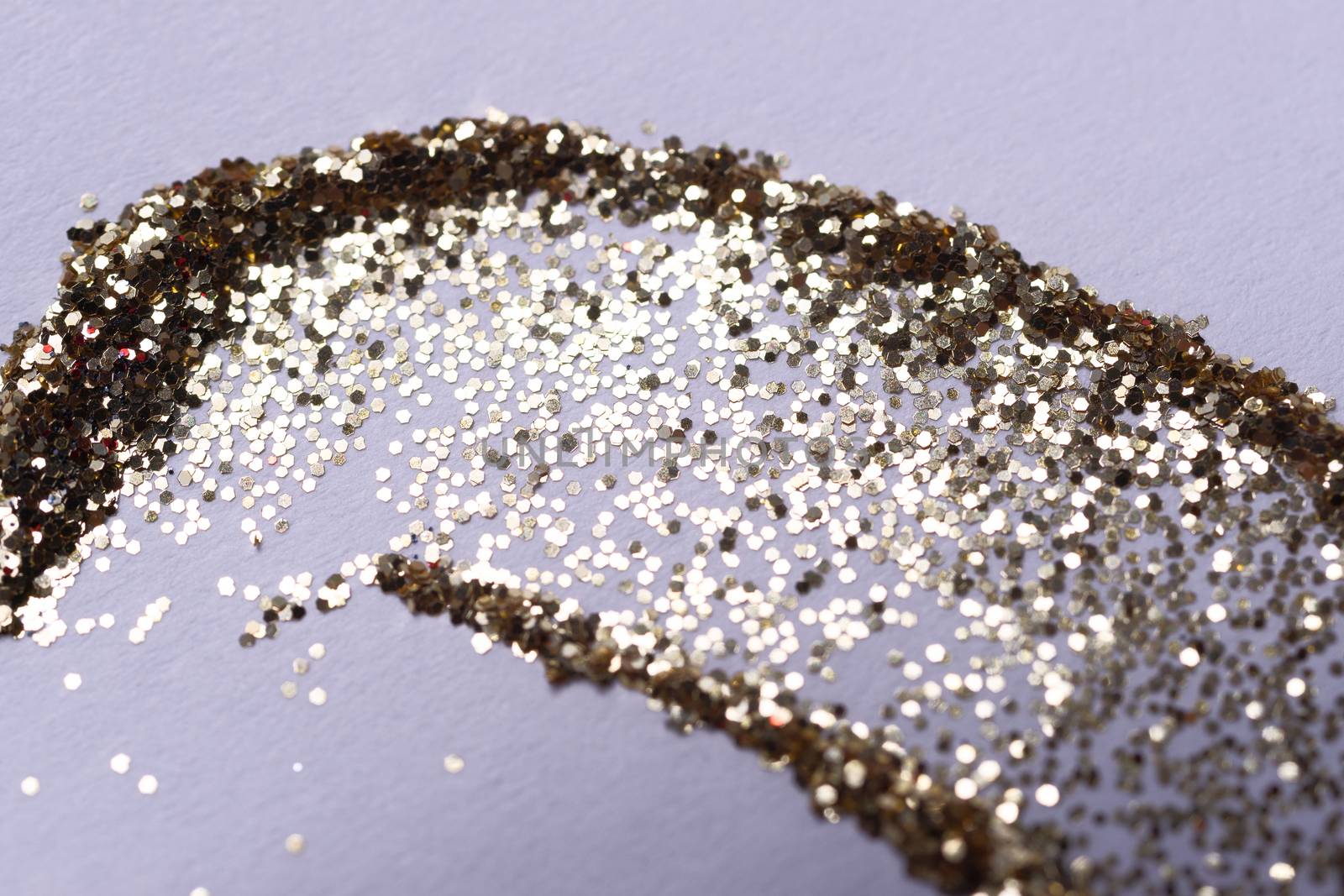 A golden nail gritter for manicure. Yellow tone glitter shining on daylight. Stock photo isolated on white background. Varnish topping on paper. Up to down view.