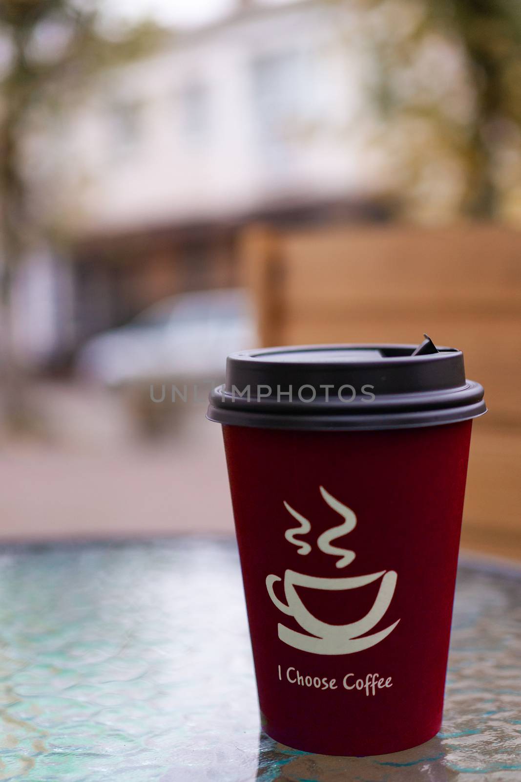 Red coffee paper cup on glass clear table. On cup wrote: "I choose coffee". Beginning a good day!
