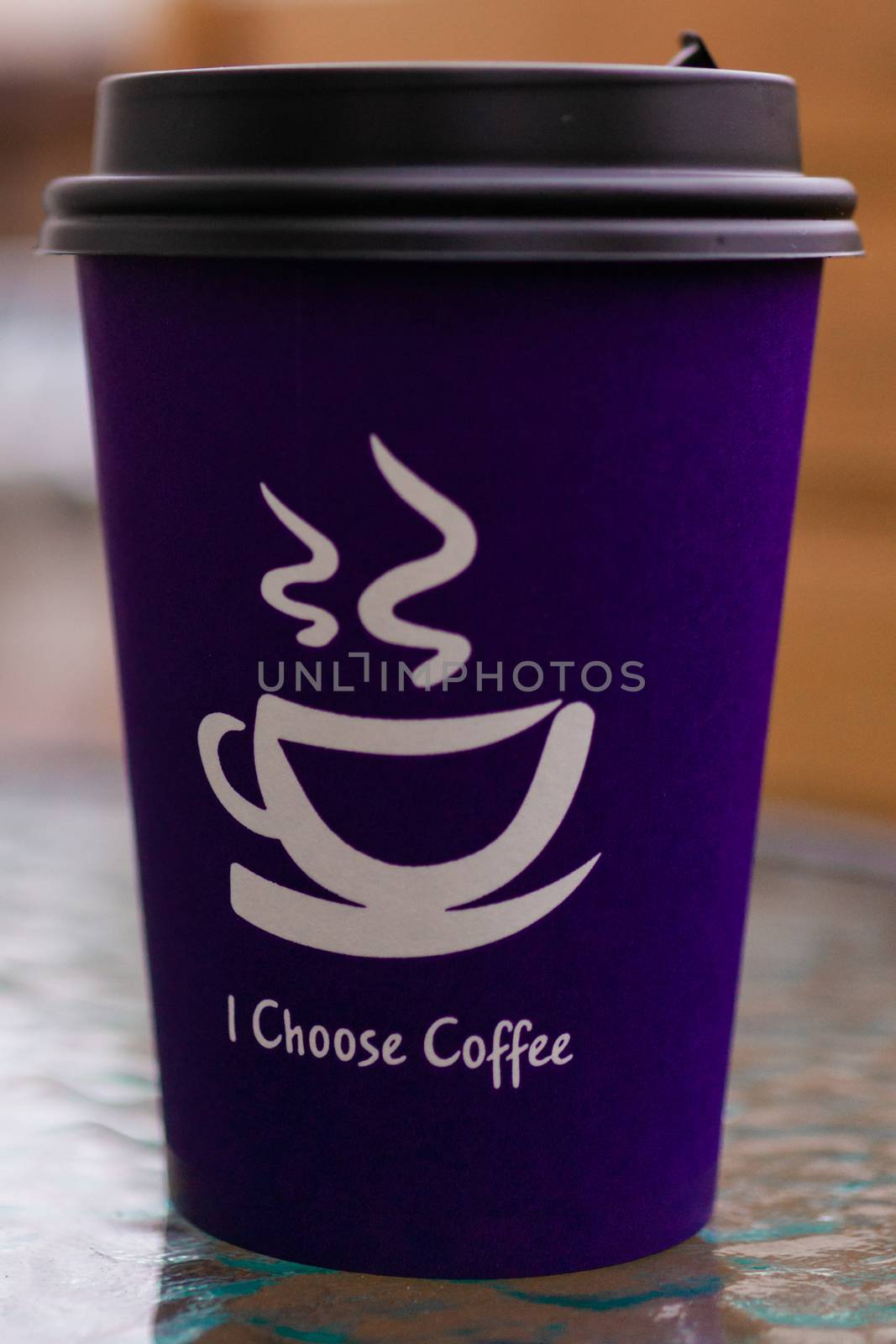 Purple coffee paper cup on glass clear table. On cup wrote: "I choose coffee". Beginning a good day!