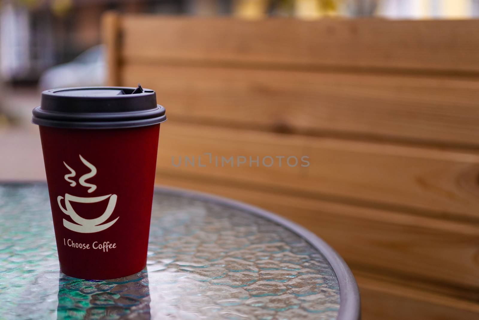 Red coffee paper cup on glass clear table. On cup wrote: "I choose coffee". Beginning a good day!