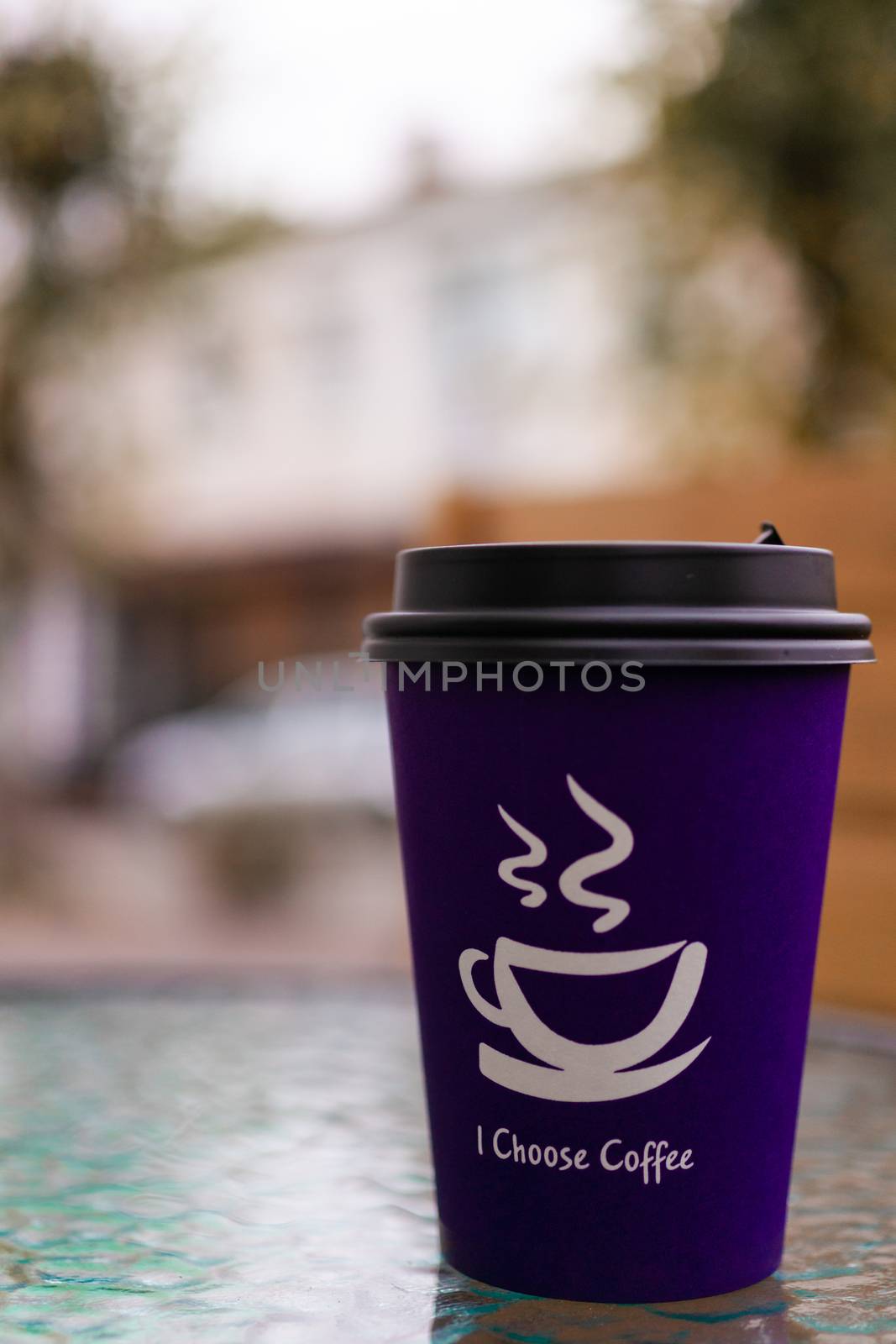 Purple coffee paper cup on glass clear table. On cup wrote: "I choose coffee". Beginning a good day!