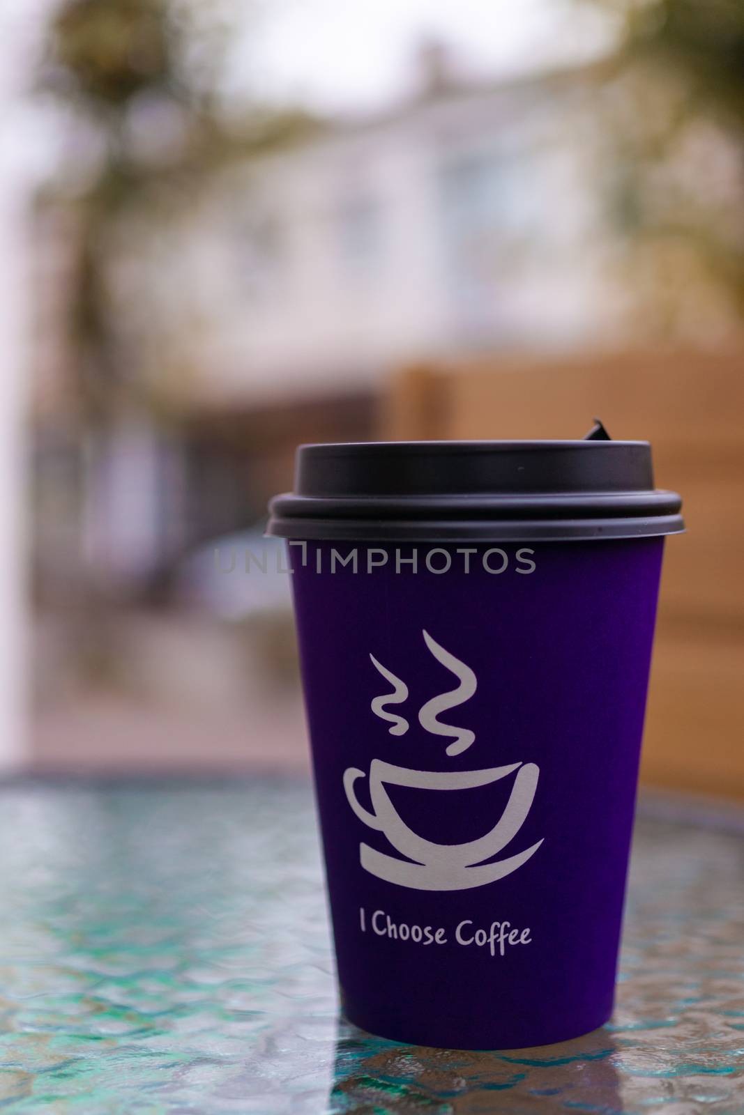 Purple coffee paper cup on glass clear table. On cup wrote: "I choose coffee". Beginning a good day!