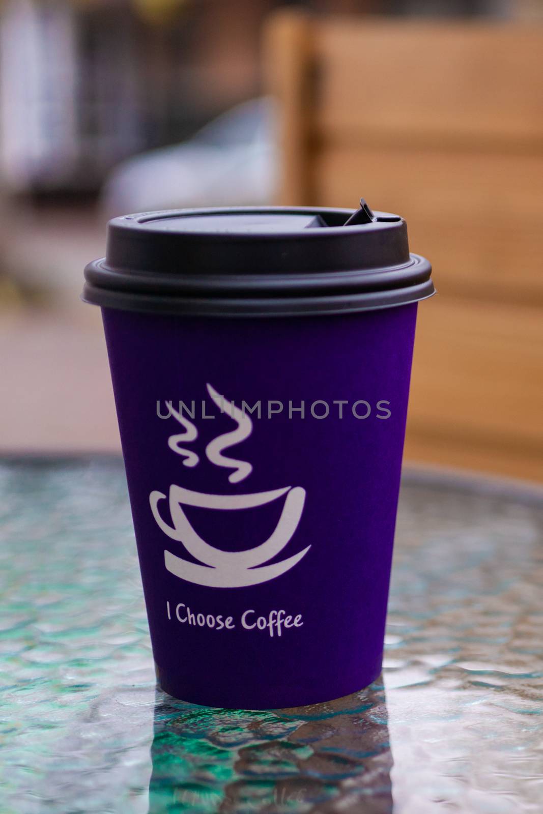 Purple coffee paper cup on glass clear table. On cup wrote: "I choose coffee". Beginning a good day!