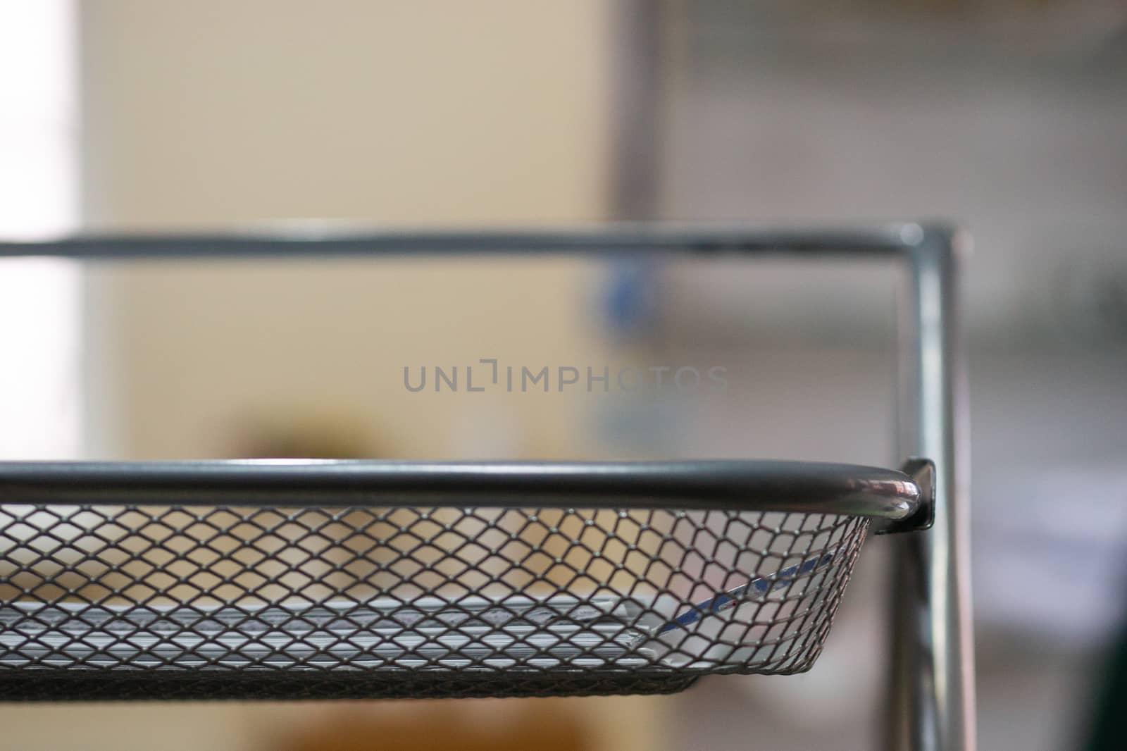 Office metal paper holder on table. Blurred background, partially defocused photo.