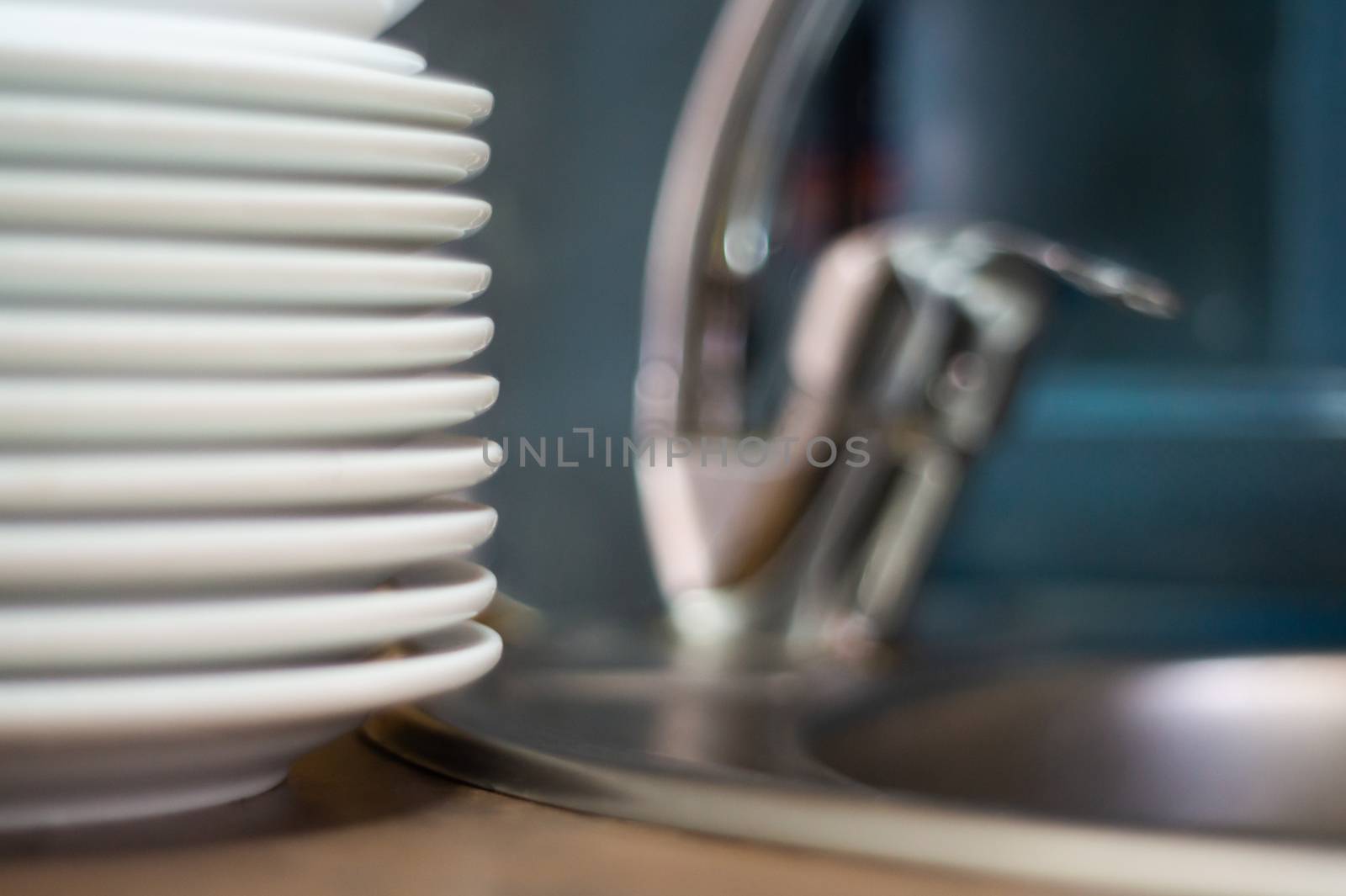 A lot of clean dish on table near sink in cafe. Close-up view