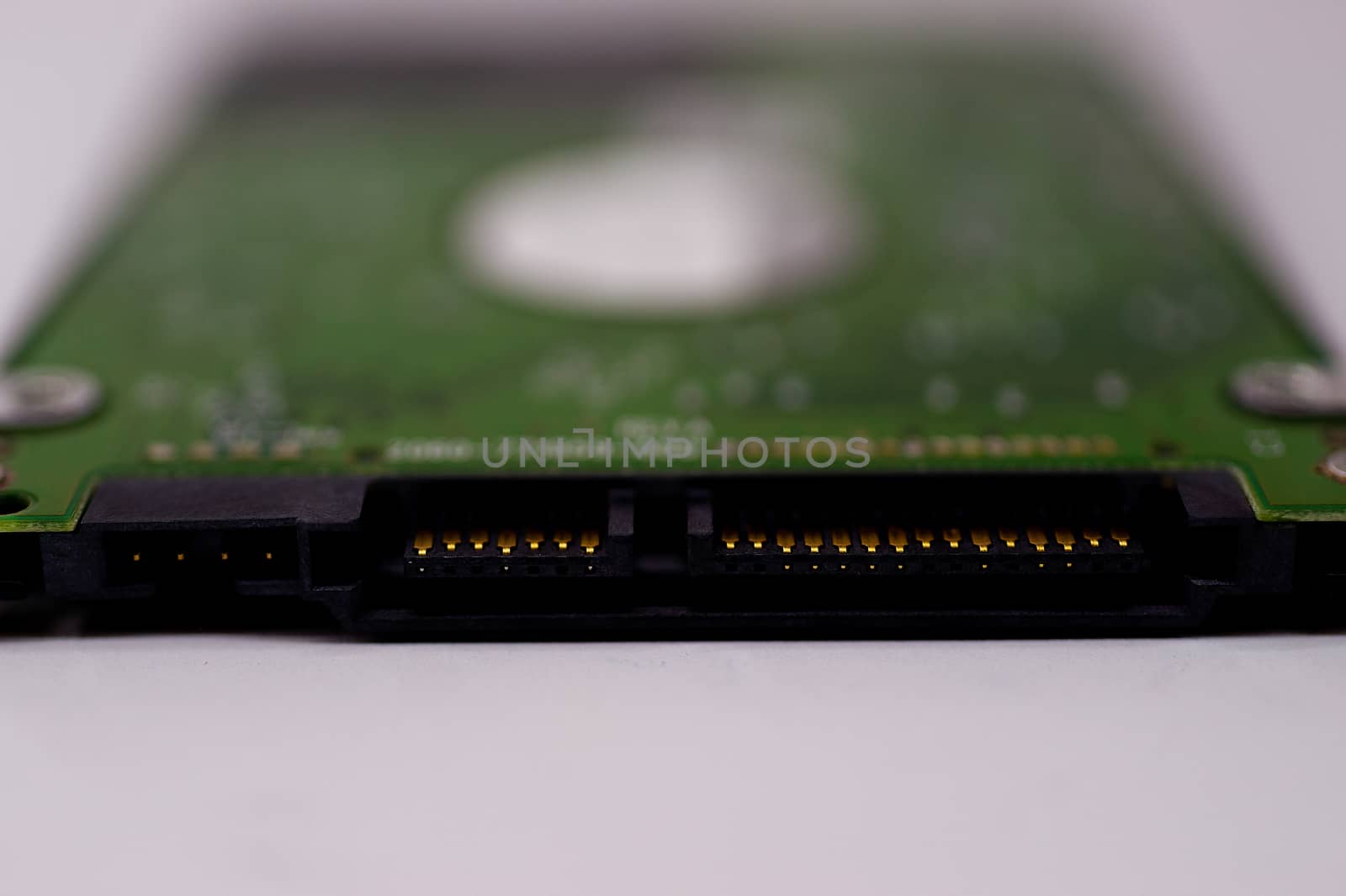 2.5mm laptop HDD on white blurred background. A lot of space on photo is defocused or have soft focus.