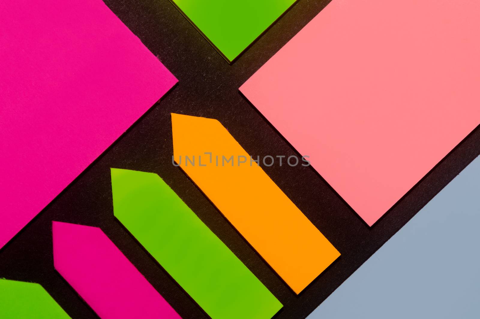 Green, orange, blue, purple and rose hue colorful office stickers on black paper. Office noteparer as reminder. Isolated on black paper.