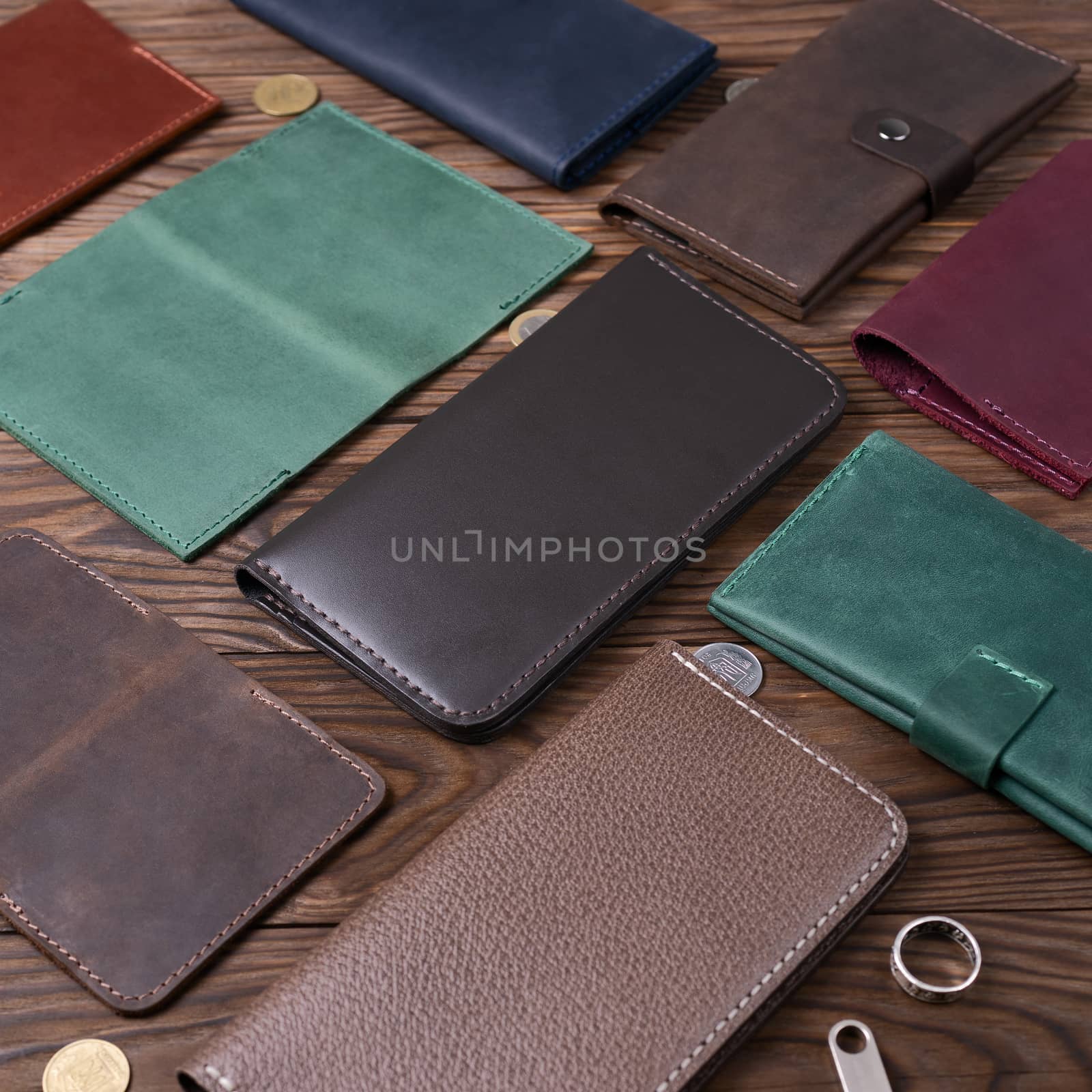 Brown gloss handmade leather porte-monnaie surrounded by other leather accessories on wooden textured background. Side view. Stock photo of luxury accessories.