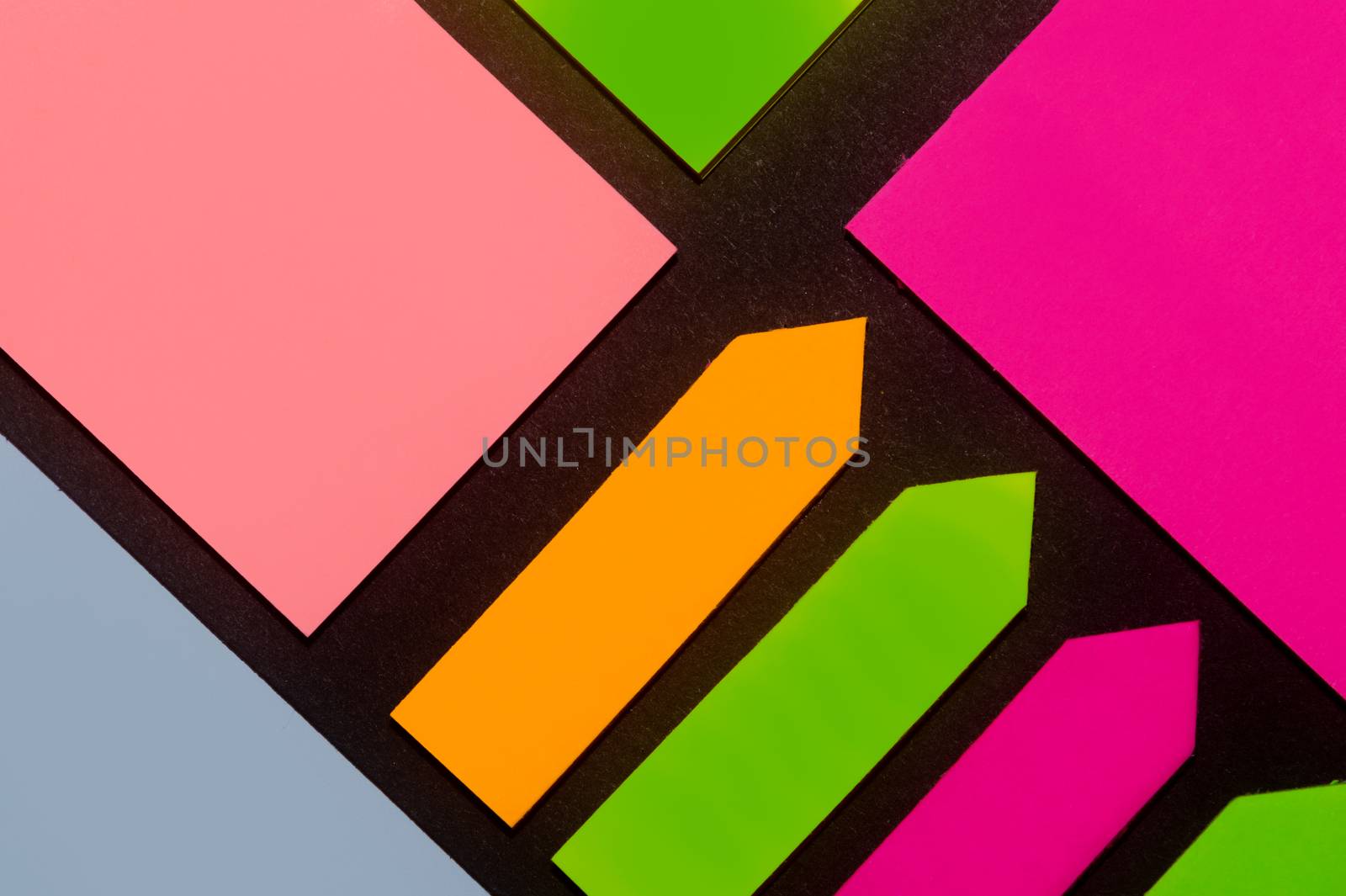 Green, orange, blue, purple and rose hue colorful office stickers on black paper. Office noteparer as reminder. Isolated on black paper.