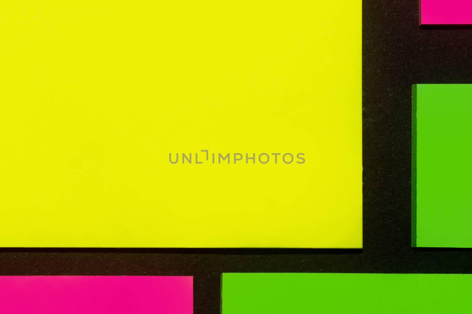 Green, yellow and purple hue colorful office stickers on black paper. Office noteparer as reminder. Isolated on black paper.