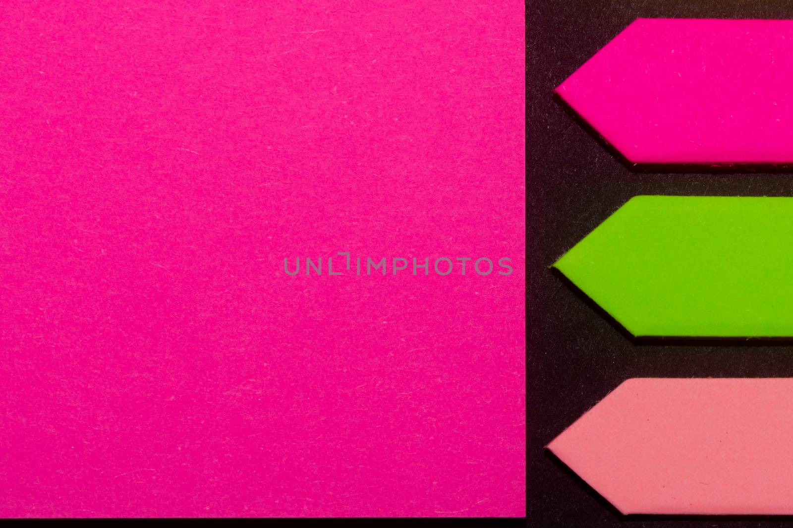 Green, purple and rose hue colorful office stickers on black paper. Office noteparer as reminder. Isolated on black paper.