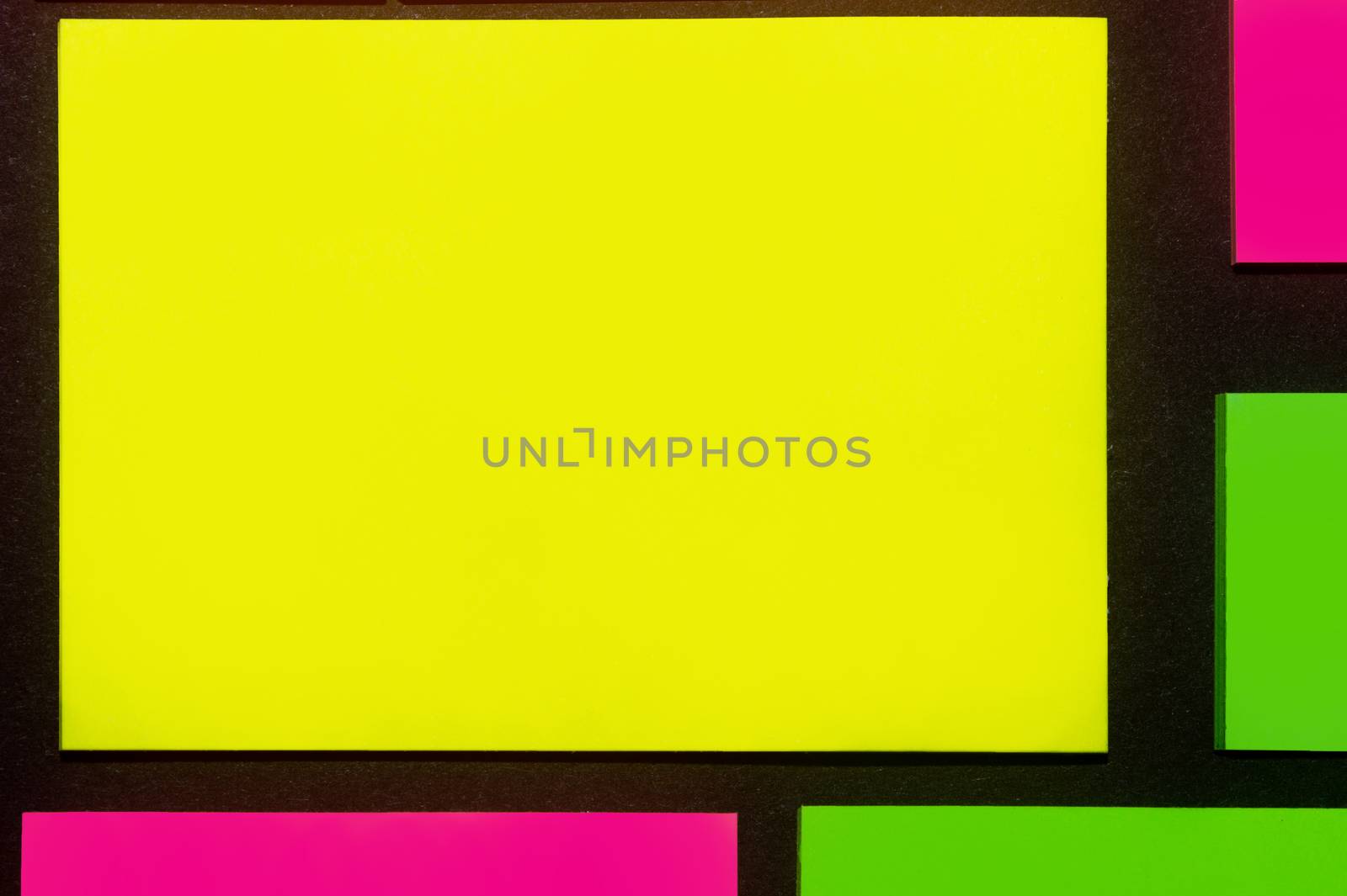 Green, yellow and purple hue colorful office stickers on black paper. Office noteparer as reminder. Isolated on black paper.