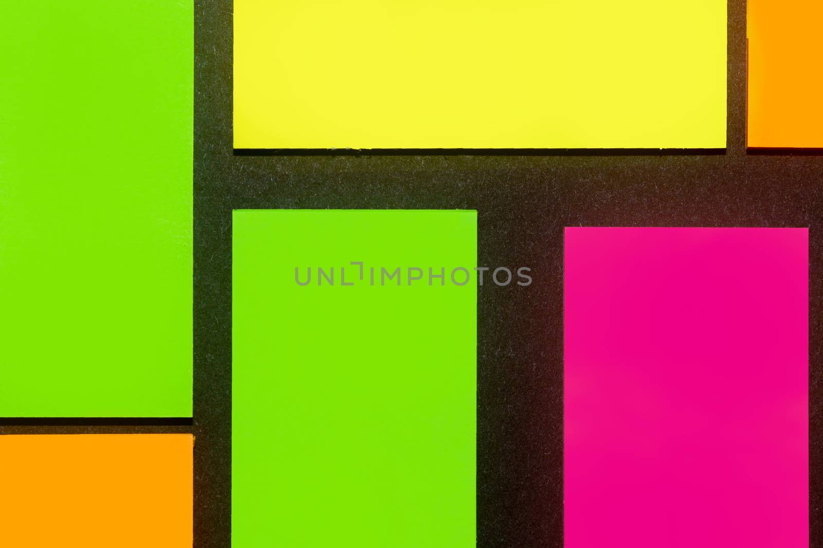 Green, yellow, orange and purple hue colorful office stickers on black paper. Office noteparer as reminder. Isolated on black paper.