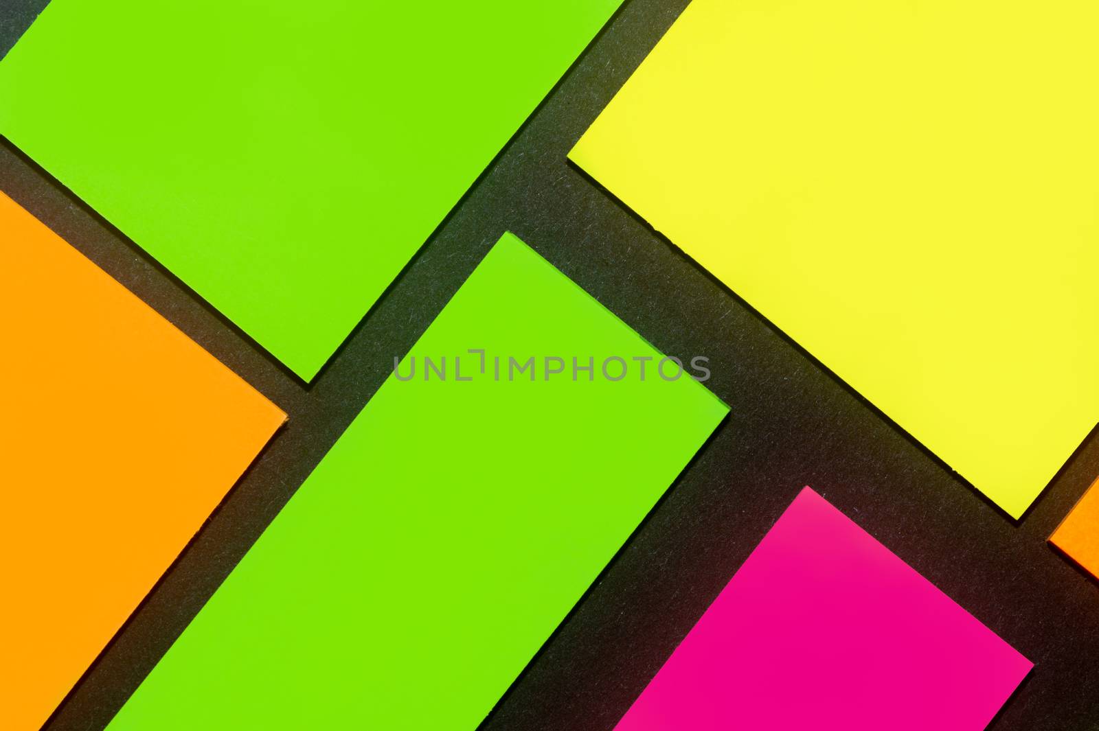 Green, yellow, orange and purple hue colorful office stickers on black paper. Office noteparer as reminder. Isolated on black paper.