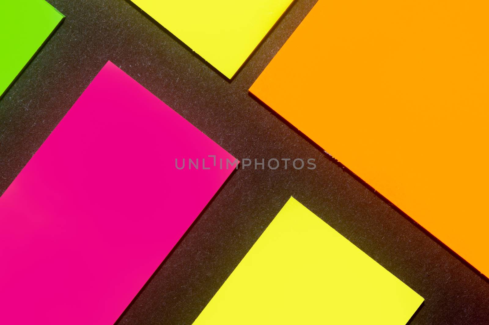 Green, yellow, orange and purple hue colorful office stickers on black paper. Office noteparer as reminder. Isolated on black paper.
